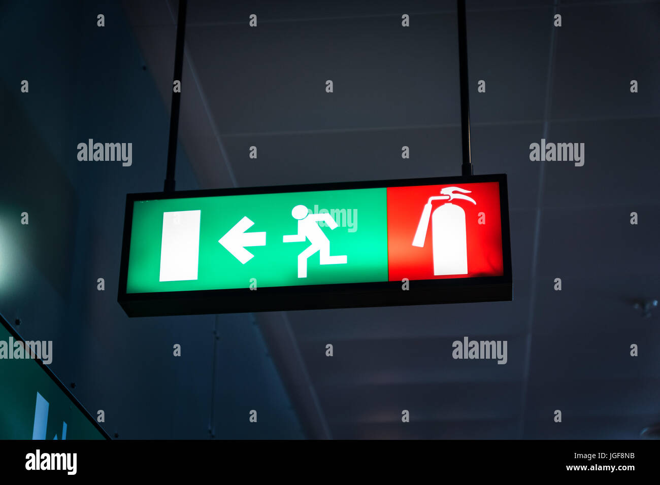 Emergency fire exit segno verde brillante in oscurati background in aeroporto Foto Stock