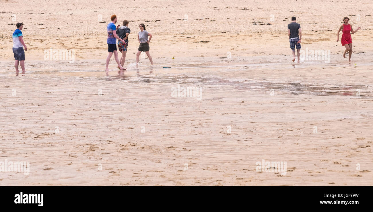 Persone su una spiaggia. Giovani vacanzieri che si diverte sulla spiaggia di Harlyn Bay in Cornovaglia. Foto Stock