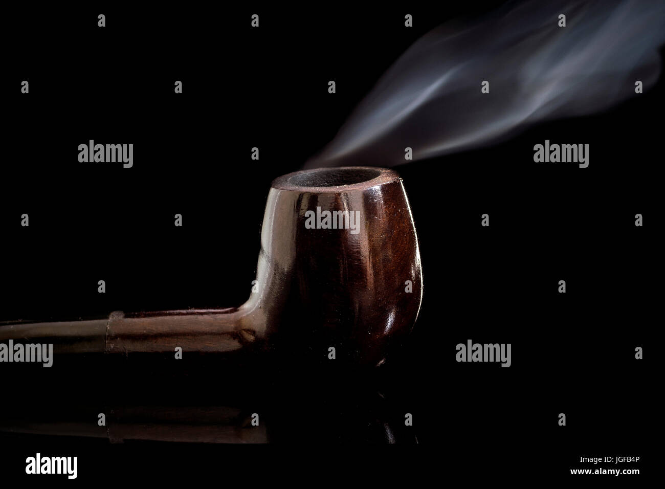 Accesa al fumo di tabacco tubo di vetro riflettente superficie, con lo spostamento di fumo, chiave di basso sfondo nero Foto Stock