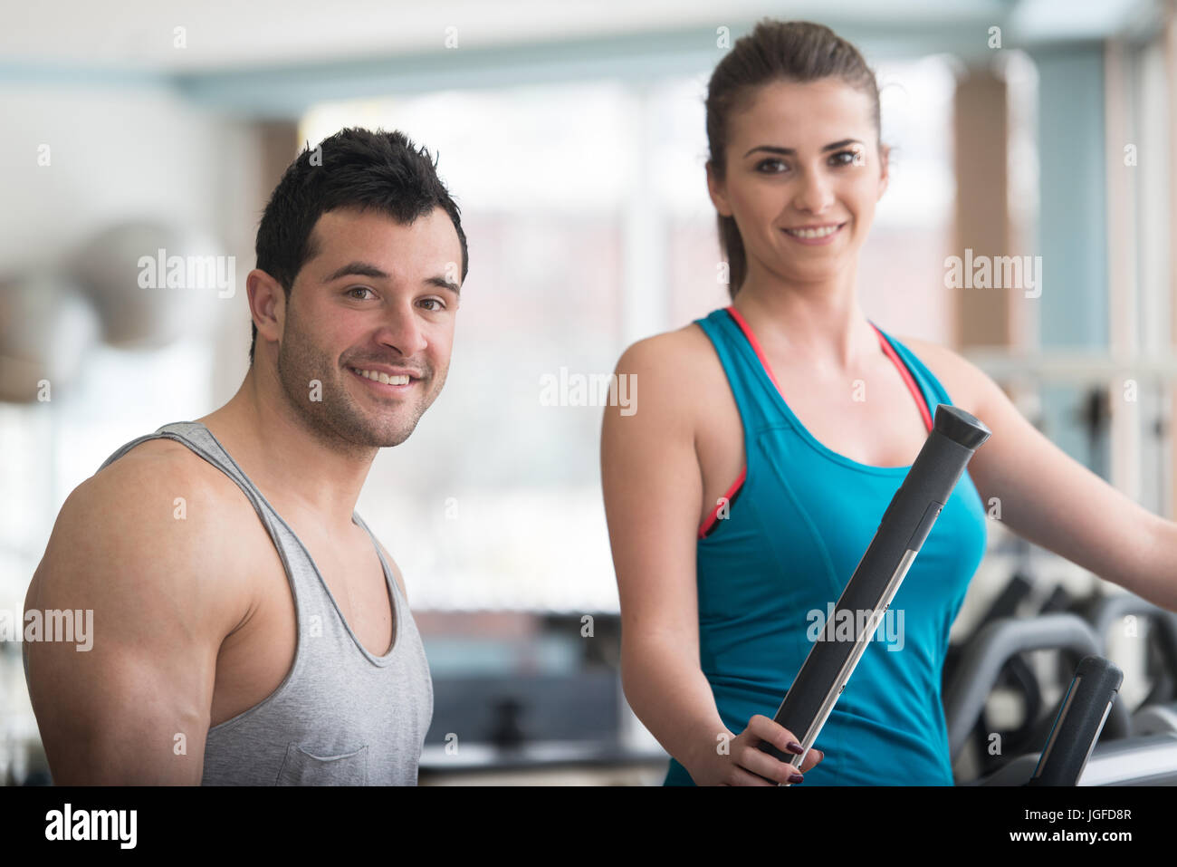 Gruppo di persone che esercitano sul camminatore ellittico in palestra o Fitness Club mentre Personal Trainer con appunti guardando li - gruppo di donne e uomini Ex Foto Stock