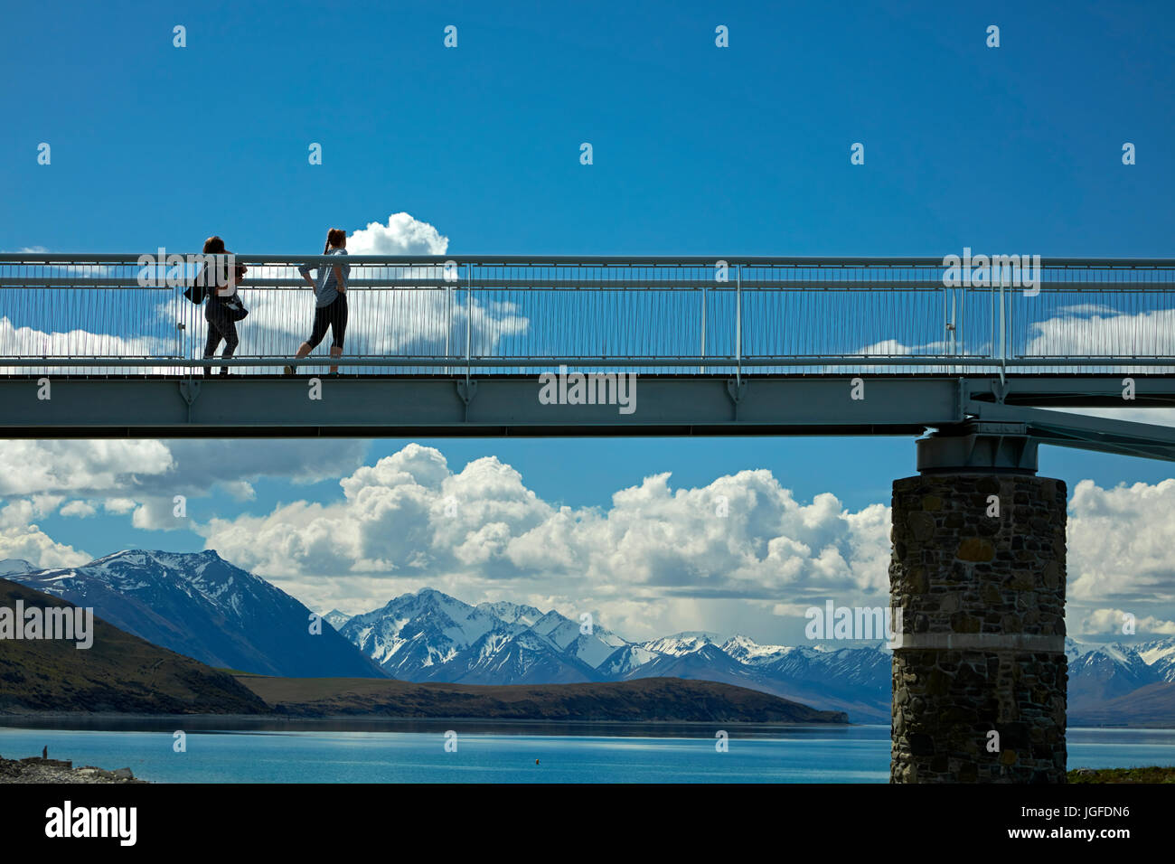 I turisti sul ponte pedonale sul Lago Tekapo uscita verso la Chiesa del Buon Pastore, Mackenzie Country, Canterbury, Isola del Sud, Nuova Zelanda Foto Stock