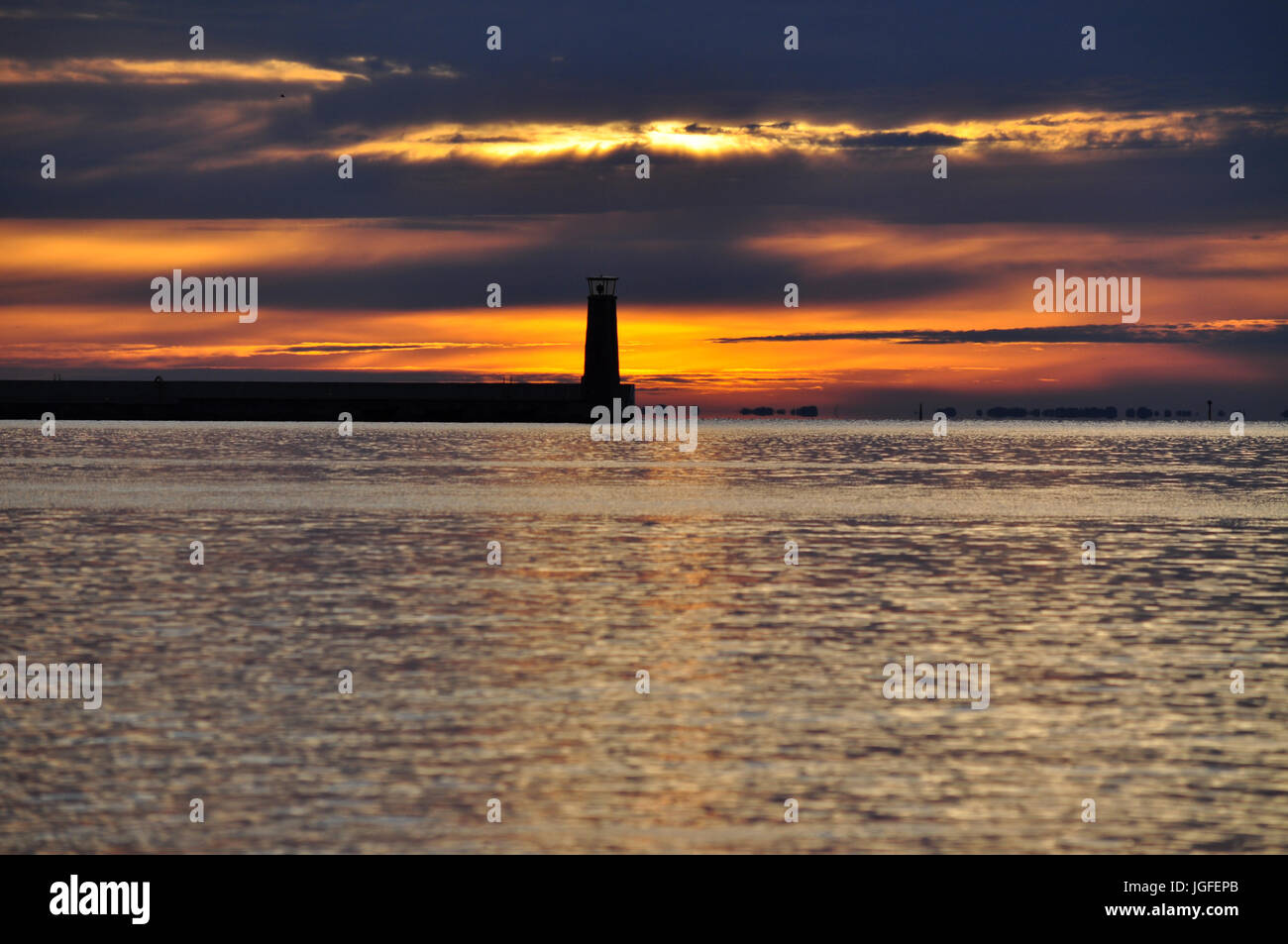 Silhouette di faro sulla vista orizzonte durante il golden Nuvoloso Tramonto sul Mar Baltico a Gdynia, Polonia Foto Stock