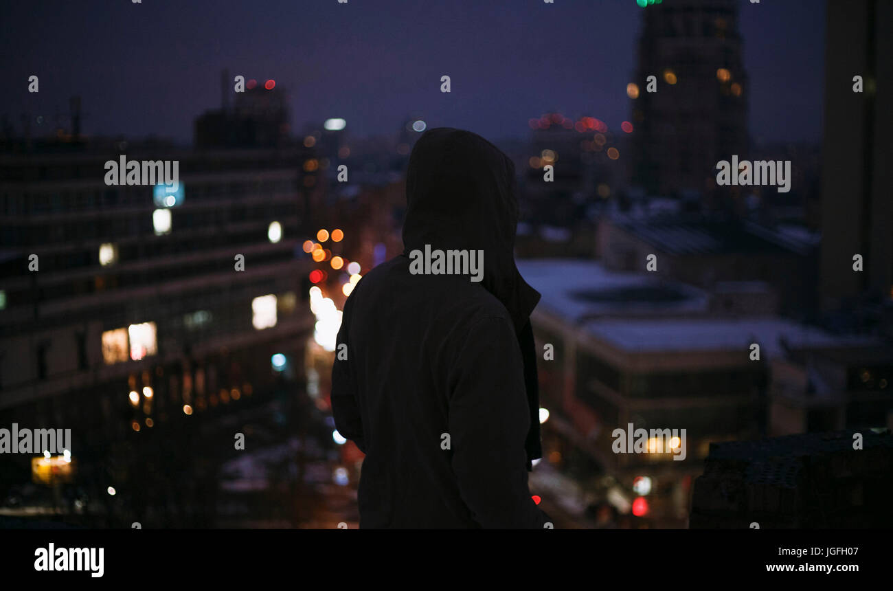 Silhouette di uomo sul tetto nella città di notte Foto Stock