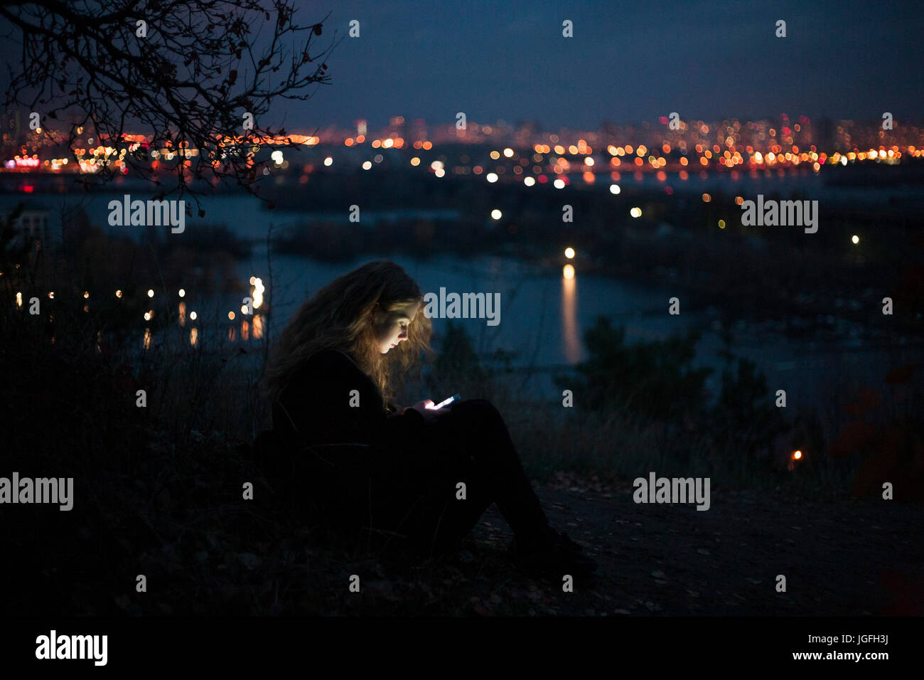 Caucasian donna in piedi vicino a waterfront urbano di notte Foto Stock