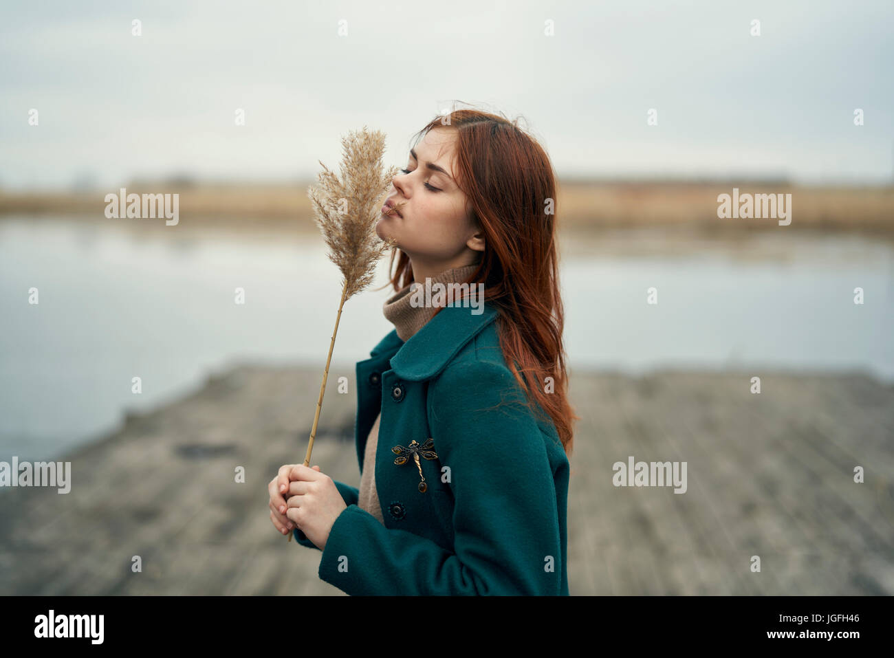 La donna caucasica permanente sulla dock levetta odore di erba Foto Stock