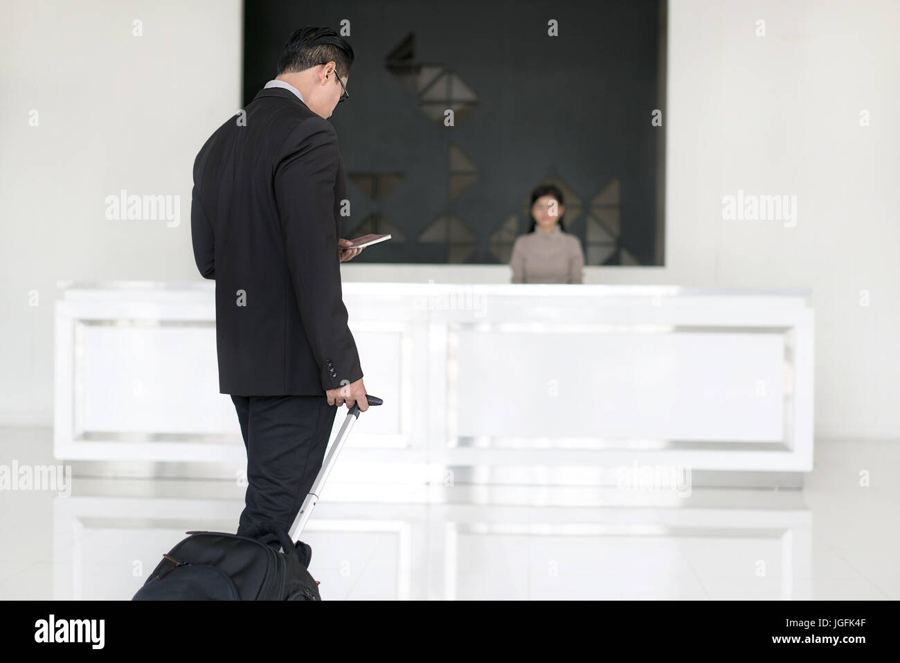Imprenditore asiatici a piedi per il check in alla reception dell'albergo reception. Foto Stock