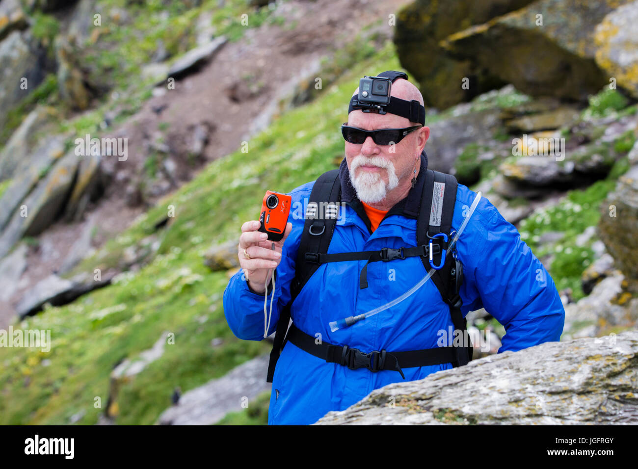 Uomo che indossa GoPro Hero headcam e azienda Fuji Finepix XP fotocamera Foto Stock