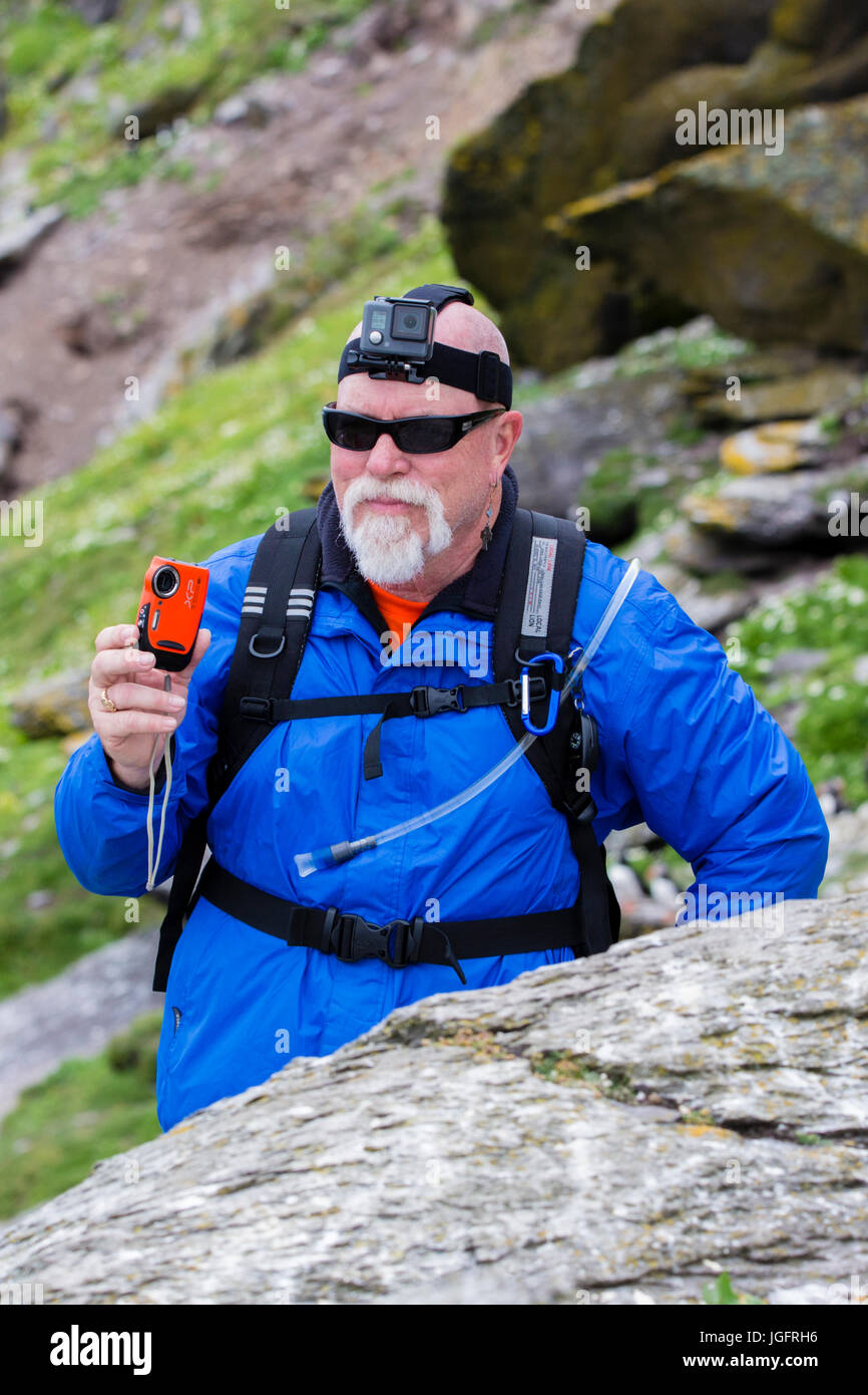 Uomo che indossa GoPro Hero headcam e azienda Fuji Finepix XP fotocamera Foto Stock