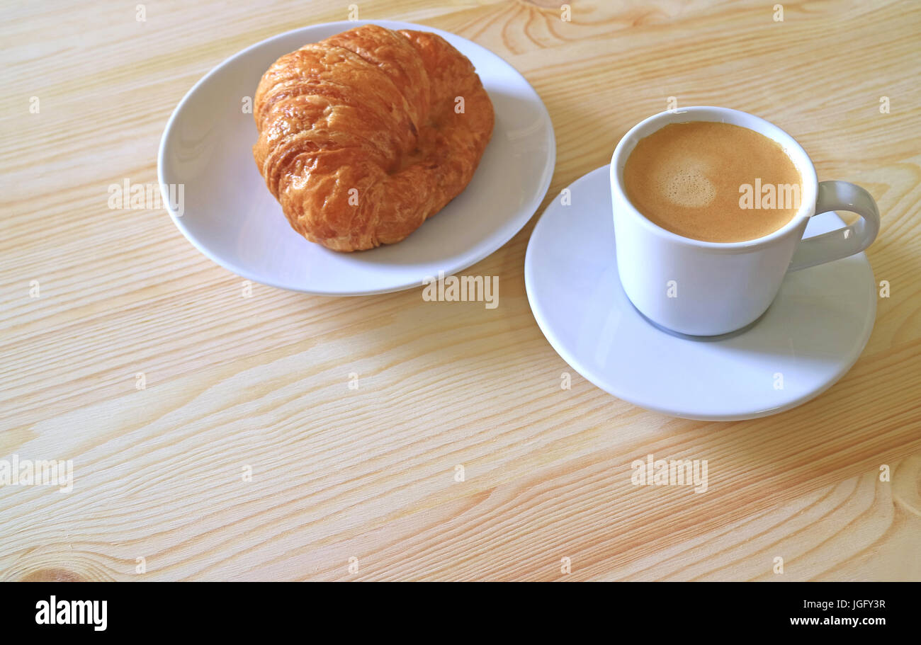 Un croissant al burro e una tazza di caffè caldo servito su un tavolo di legno, con spazio libero lo spazio per testo e Design Foto Stock
