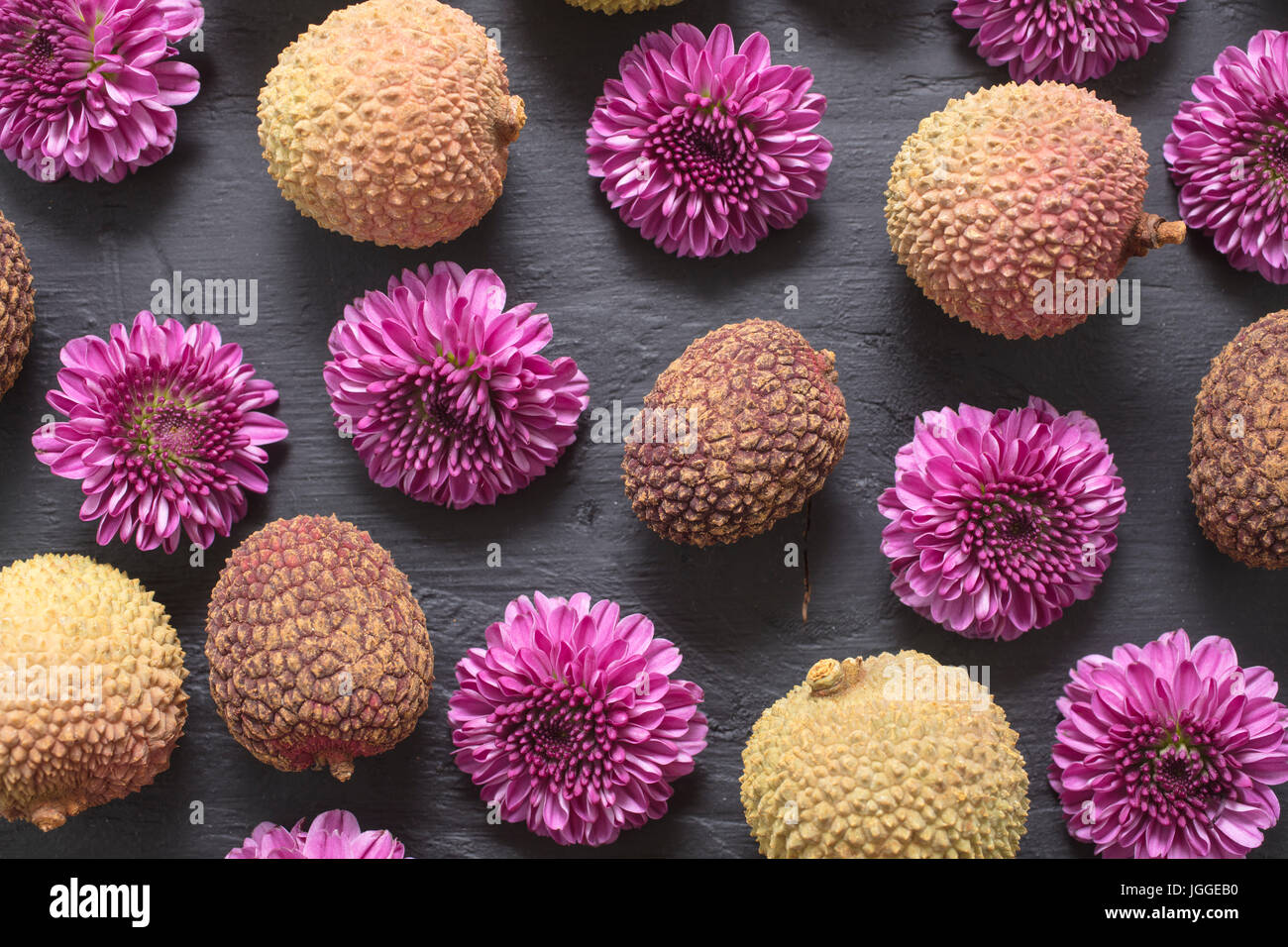 Raggruppamento di litchi frutto e il giardino di viola le mamme prevista su un ardesia tagliere Foto Stock