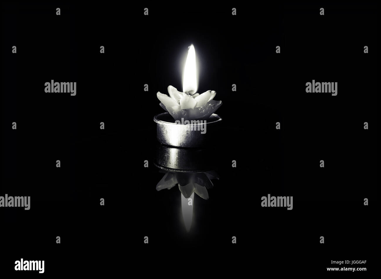 La candela di cera su uno sfondo nero con un bruciare il fusibile. Bianco e nero foto retrò. Foto Stock