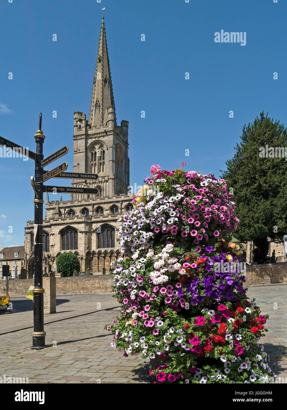 Red Lion Square e Chiesa di Tutti i Santi con fiori e dito post direzione segno, Stamford, Lincolnshire, England, Regno Unito Foto Stock