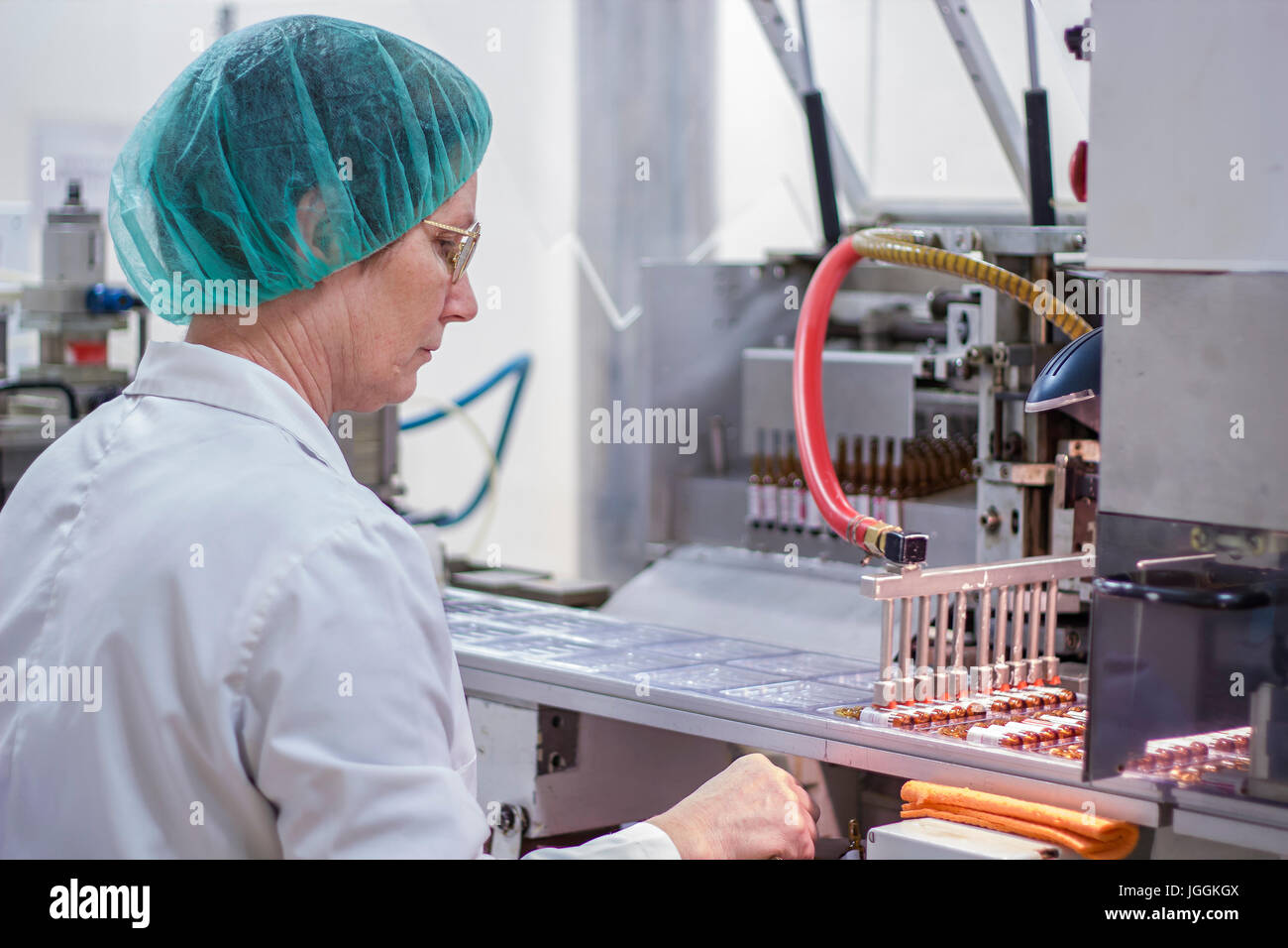 Il braccio robotico fiale di sollevamento alla linea di confezionamento in fabbrica farmaceutica. Foto Stock