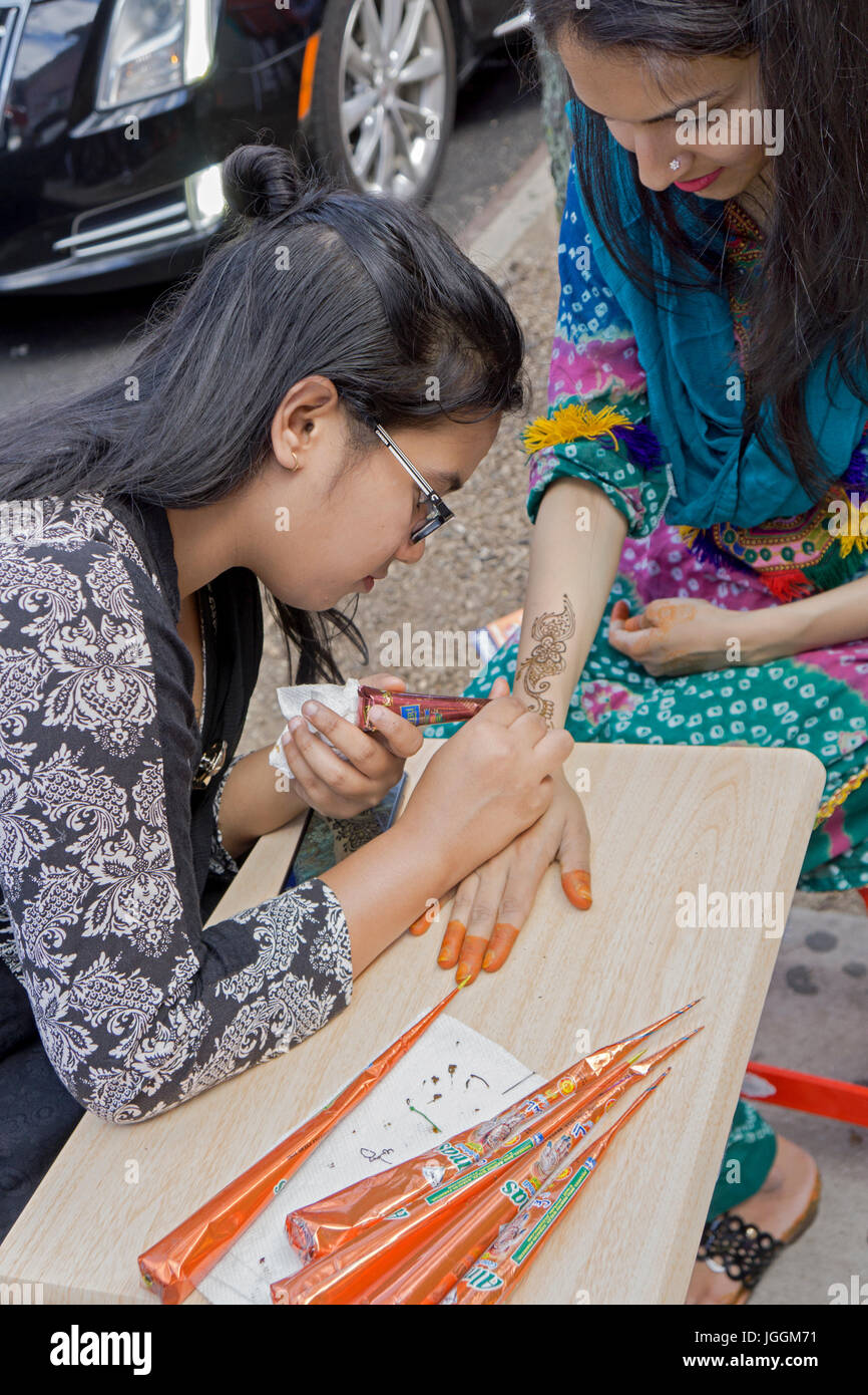 Una giovane donna applicando una mano henné tattoo per l'Eid Al Fitr Musiim vacanza. In Jackson Heights, Queens, a New York. Foto Stock