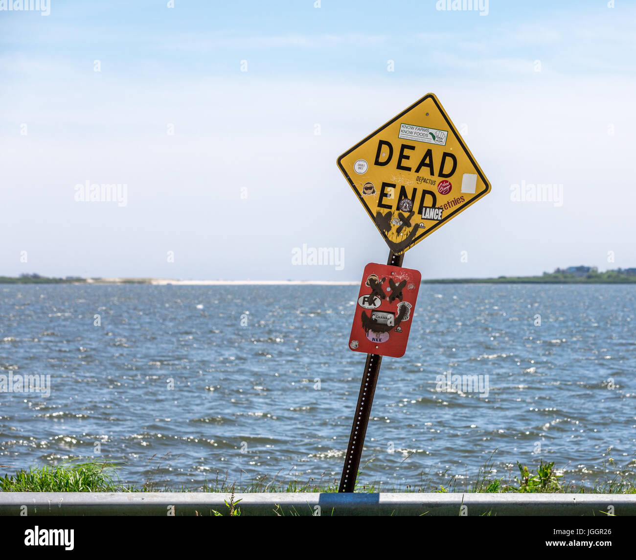 Vecchi e malandati dead end firmare alla fine di una strada con acqua dietro di essa Foto Stock