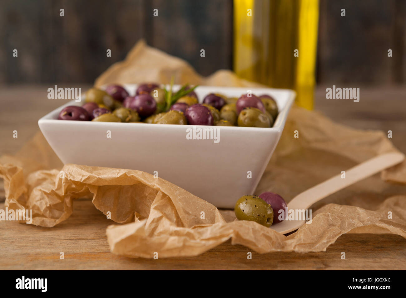 Close up di olive servita nel recipiente dal cucchiaio di legno sulla carta oleata Foto Stock