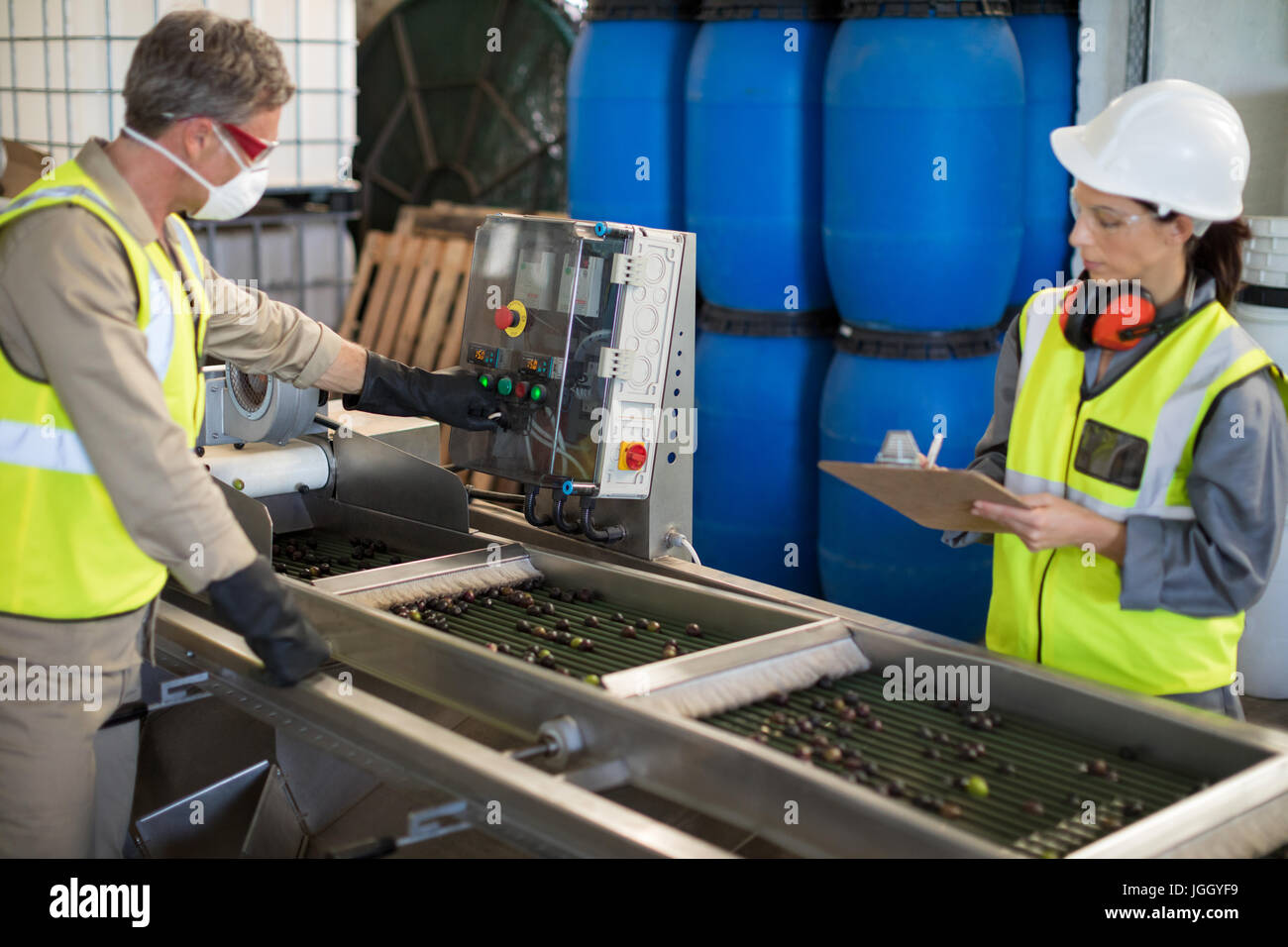 I tecnici il funzionamento della macchina durante la lavorazione di olive in fabbrica Foto Stock