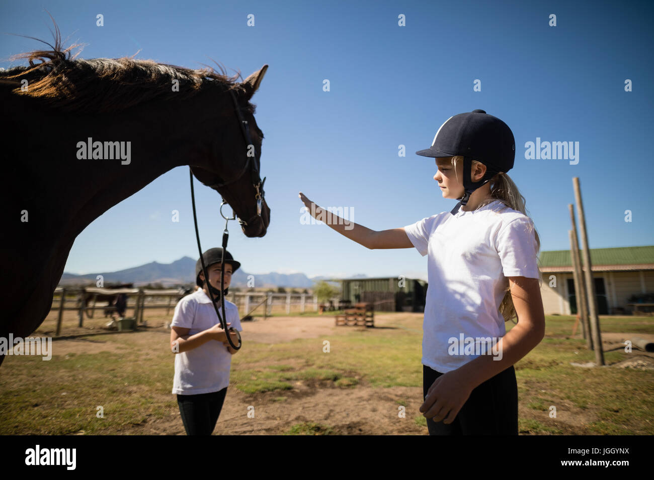 Due ragazze in piedi con un cavallo al ranch in una giornata di sole Foto Stock
