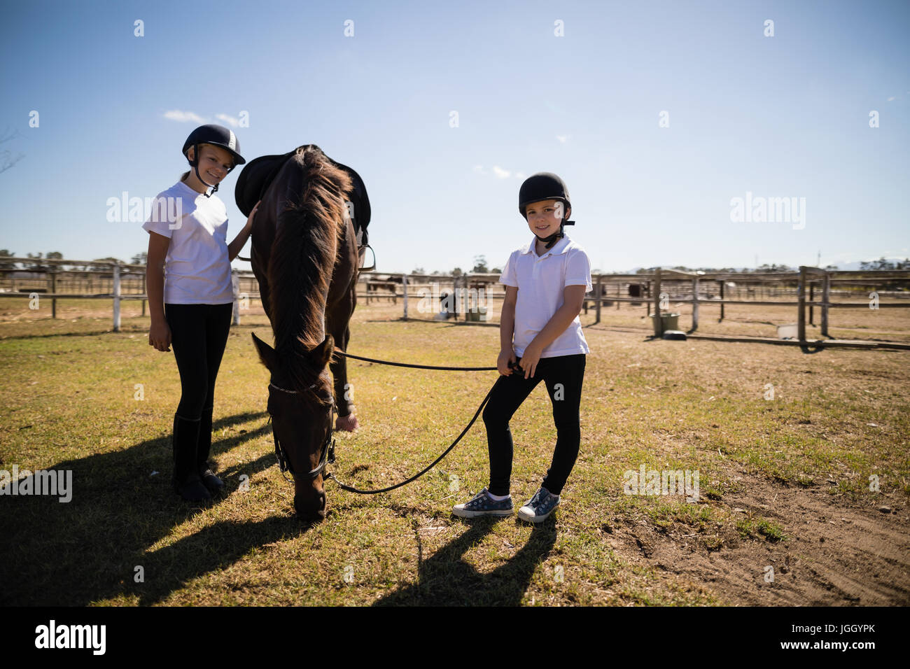 Ragazze sorridenti in piedi in ranch con casa marrone in una giornata di sole Foto Stock