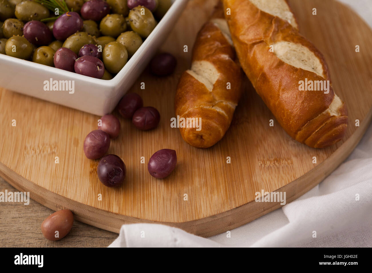 Le olive nel contenitore da pane sul tagliere con igienico Foto Stock