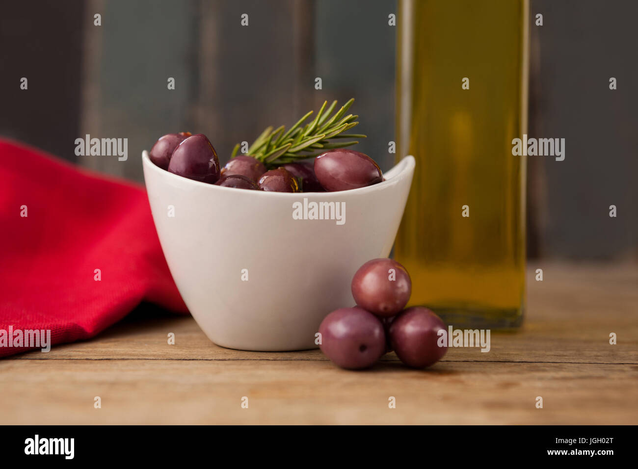 Close up di olive nel recipiente da bottiglia di olio su tavola Foto Stock