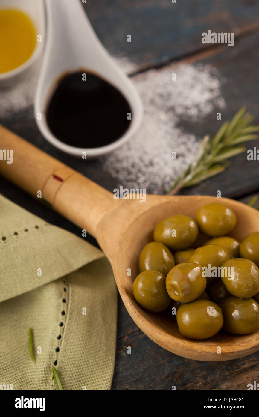 In prossimità delle olive verdi in cucchiaio di olio su tavola Foto Stock