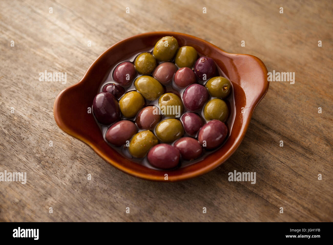 Angolo di alta vista di olive con olio nel contenitore di legno sul tavolo Foto Stock