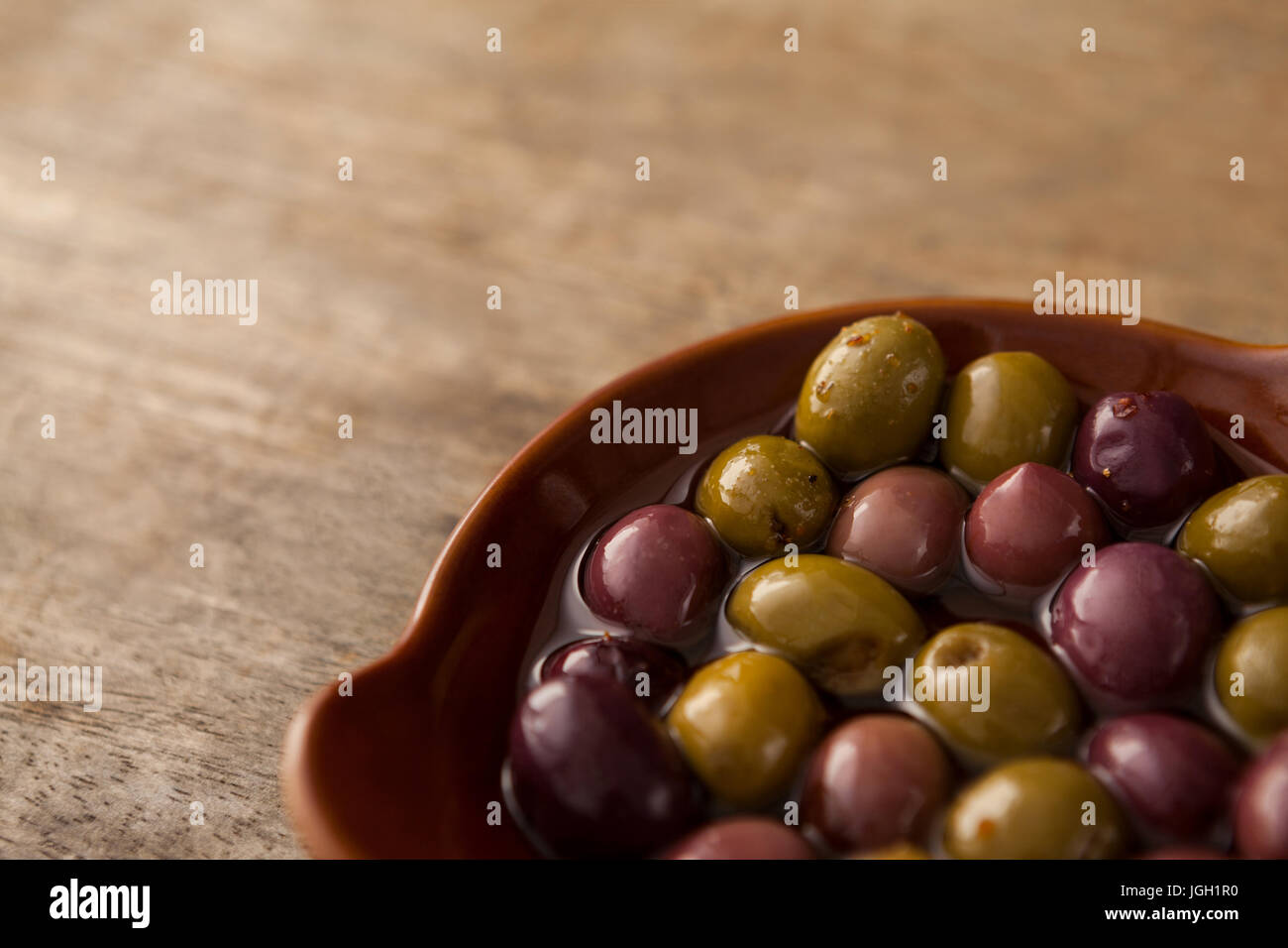 Angolo di alta vista di olive con olio nel contenitore sul tavolo di legno Foto Stock