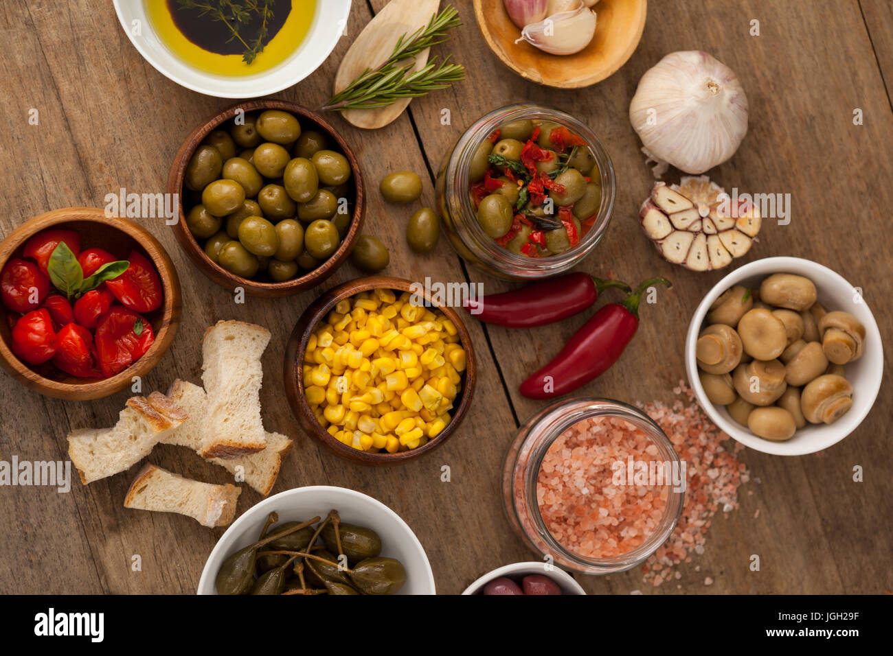 Vista aerea di olive con verdura e spezie da olio nella ciotola sul tavolo Foto Stock
