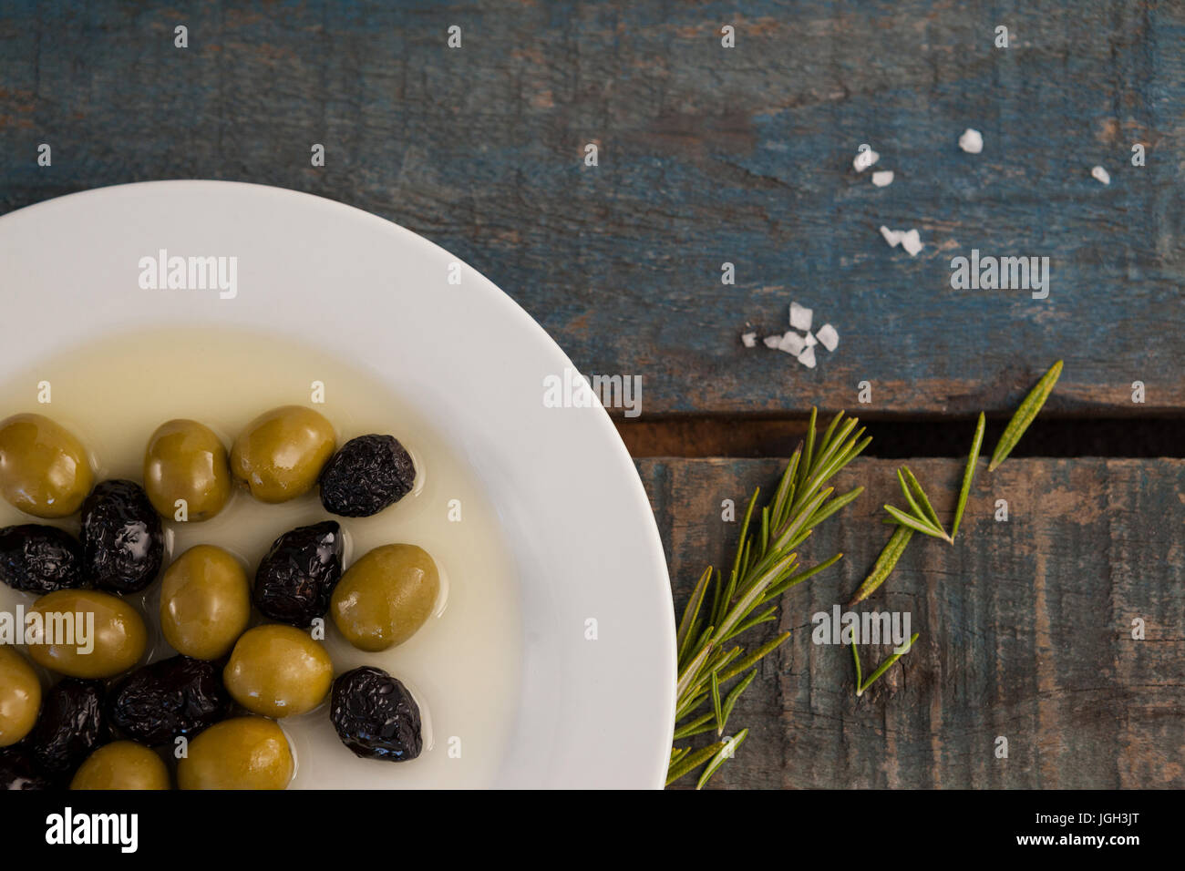 Close up di olive nella piastra con olio su tavola in legno Foto Stock