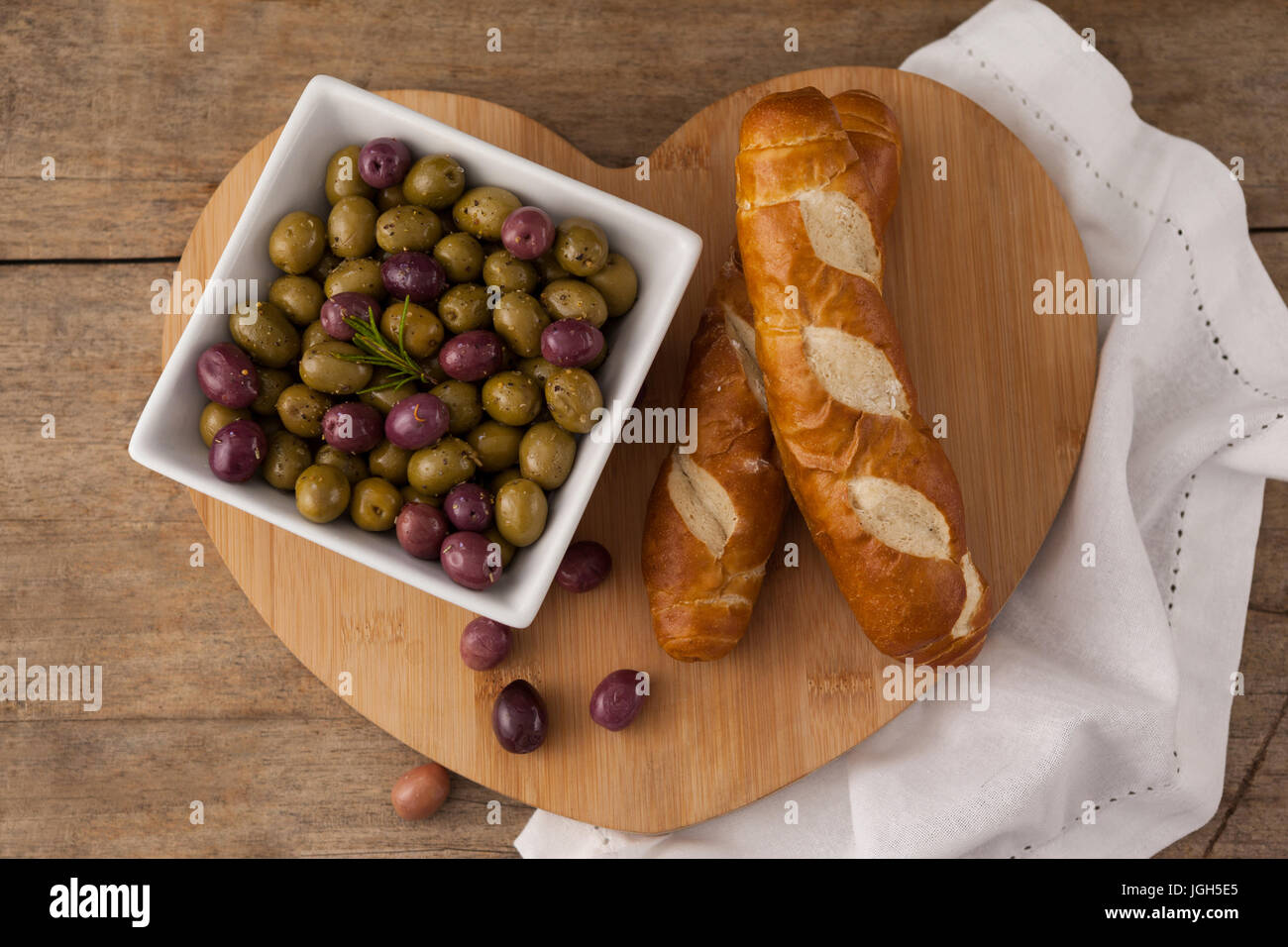 Le olive nel contenitore da pane a forma di cuore tagliere con igienico Foto Stock