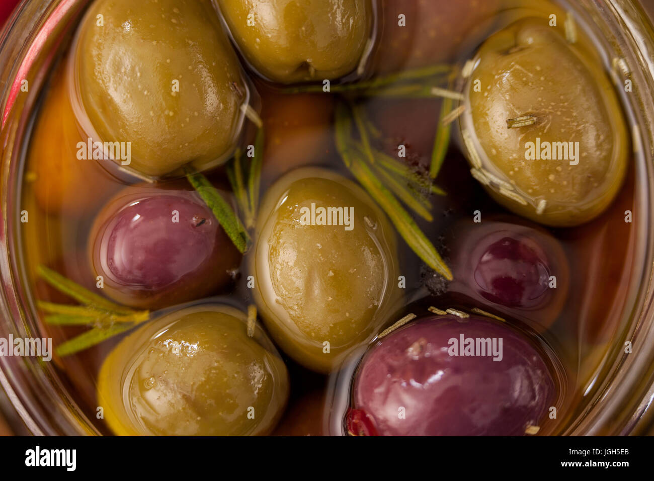 Close up di olive e le erbe con olio con contenitore in vetro Foto Stock