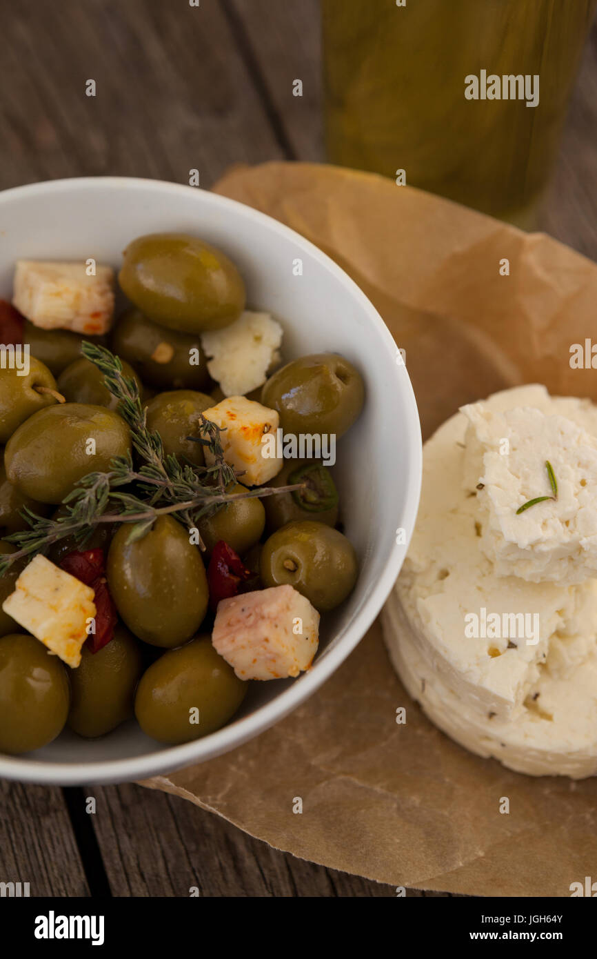 Angolo di alta vista di olive verdi con formaggio sulla carta oleata a tavola Foto Stock