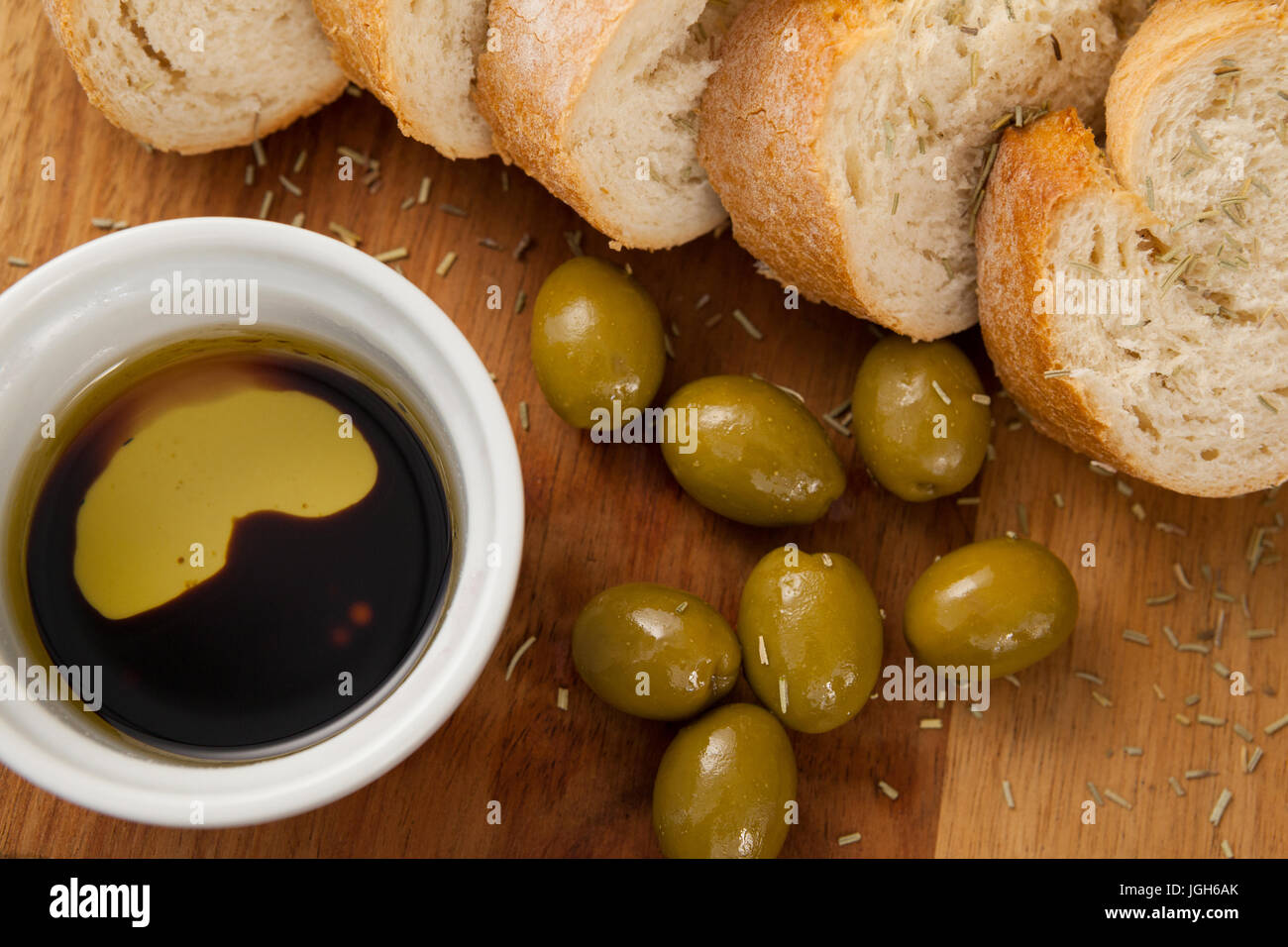 Close up di olive con pane e olio nel contenitore sul bordo di taglio Foto Stock