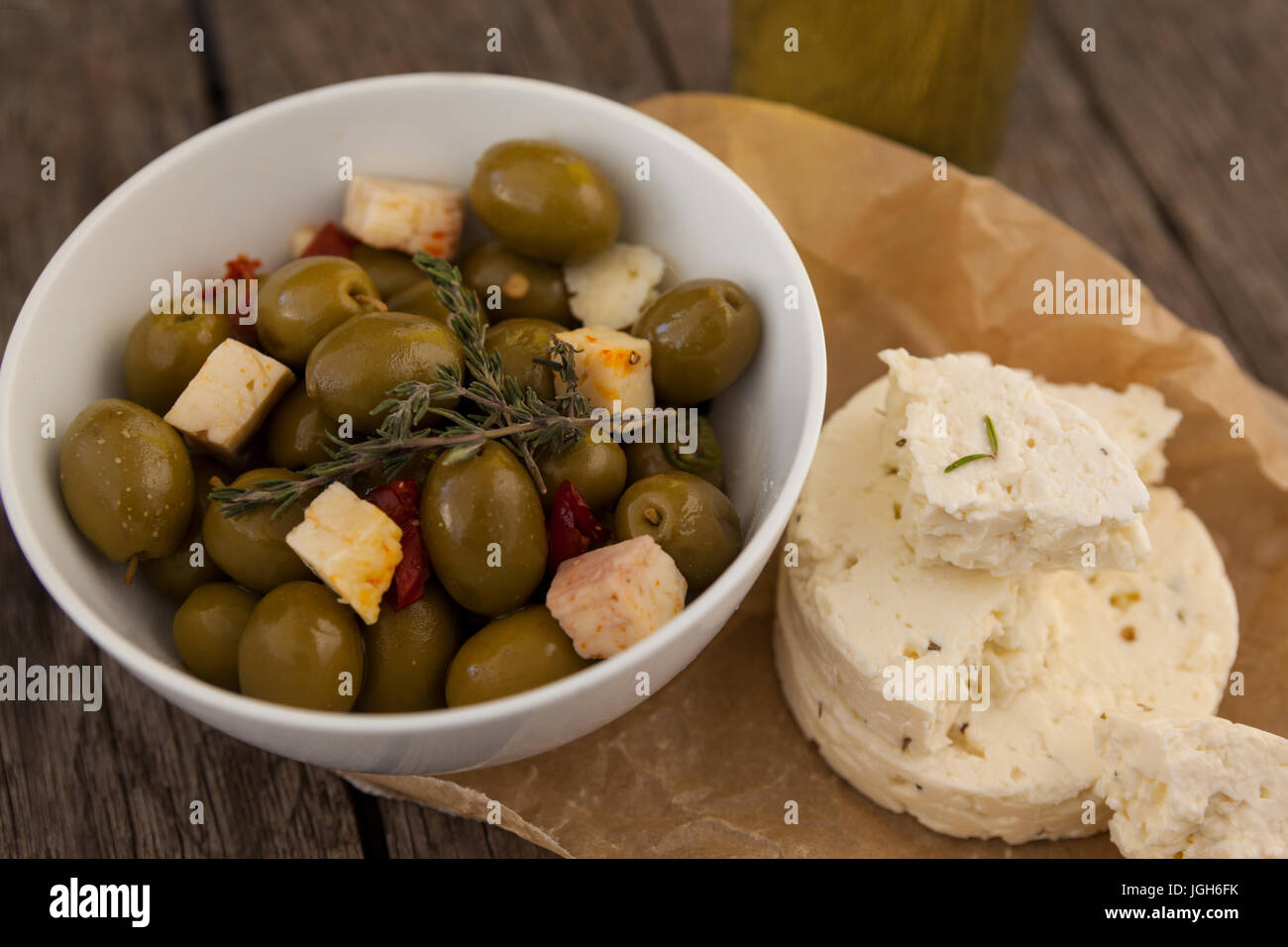 Angolo di alta vista di olive con formaggio sulla carta oleata a tavola Foto Stock