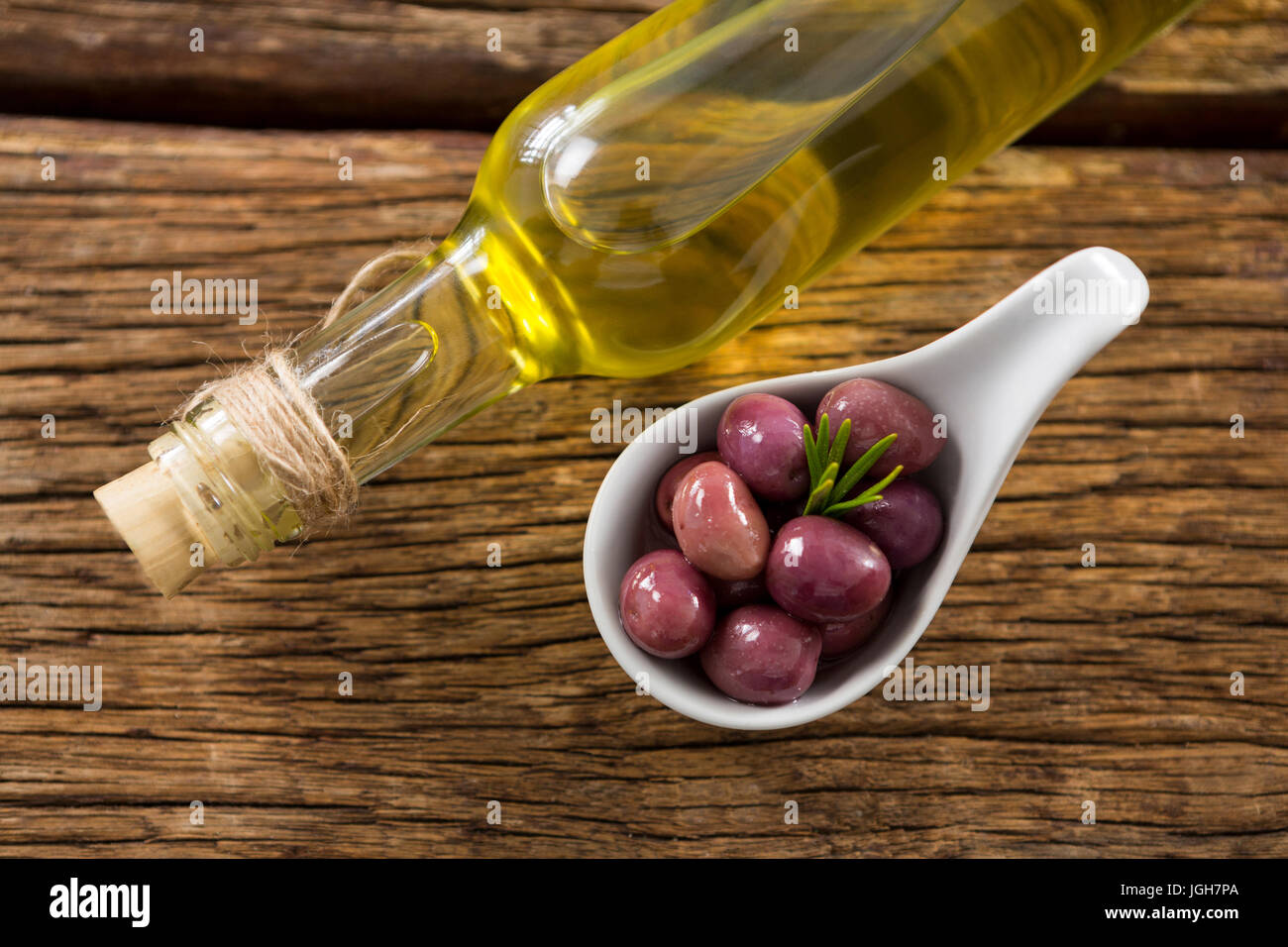 Sovraccarico di marinato e olio d'oliva Bottiglia sul tavolo di legno Foto Stock