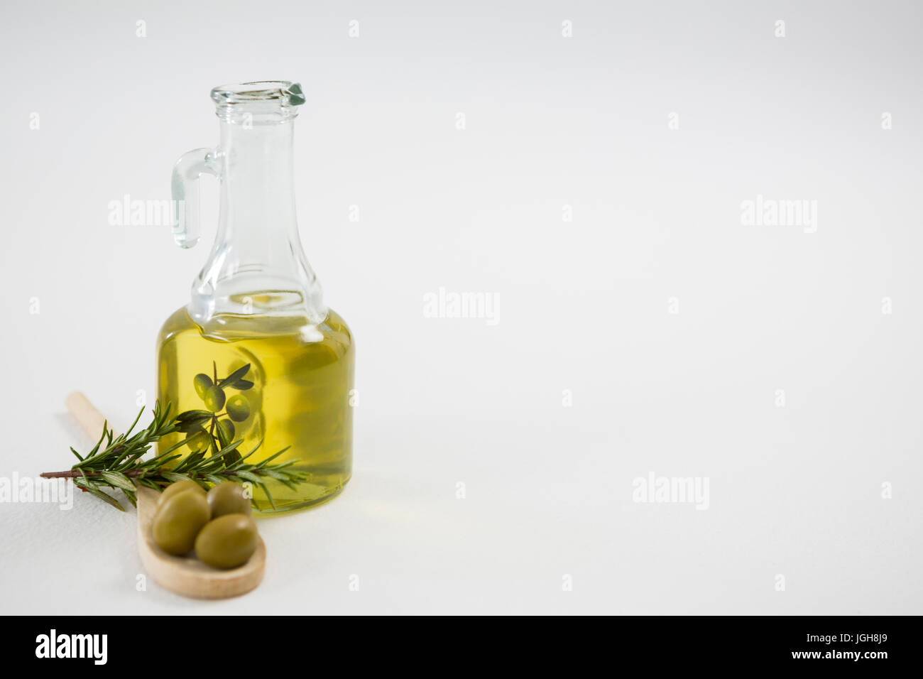 Olive marinate con bottiglia di olio e le erbe contro uno sfondo bianco Foto Stock