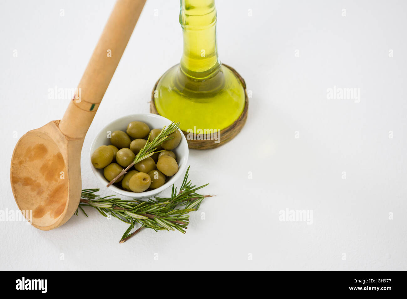 Olive marinate con bottiglia di olio e le erbe contro uno sfondo bianco Foto Stock