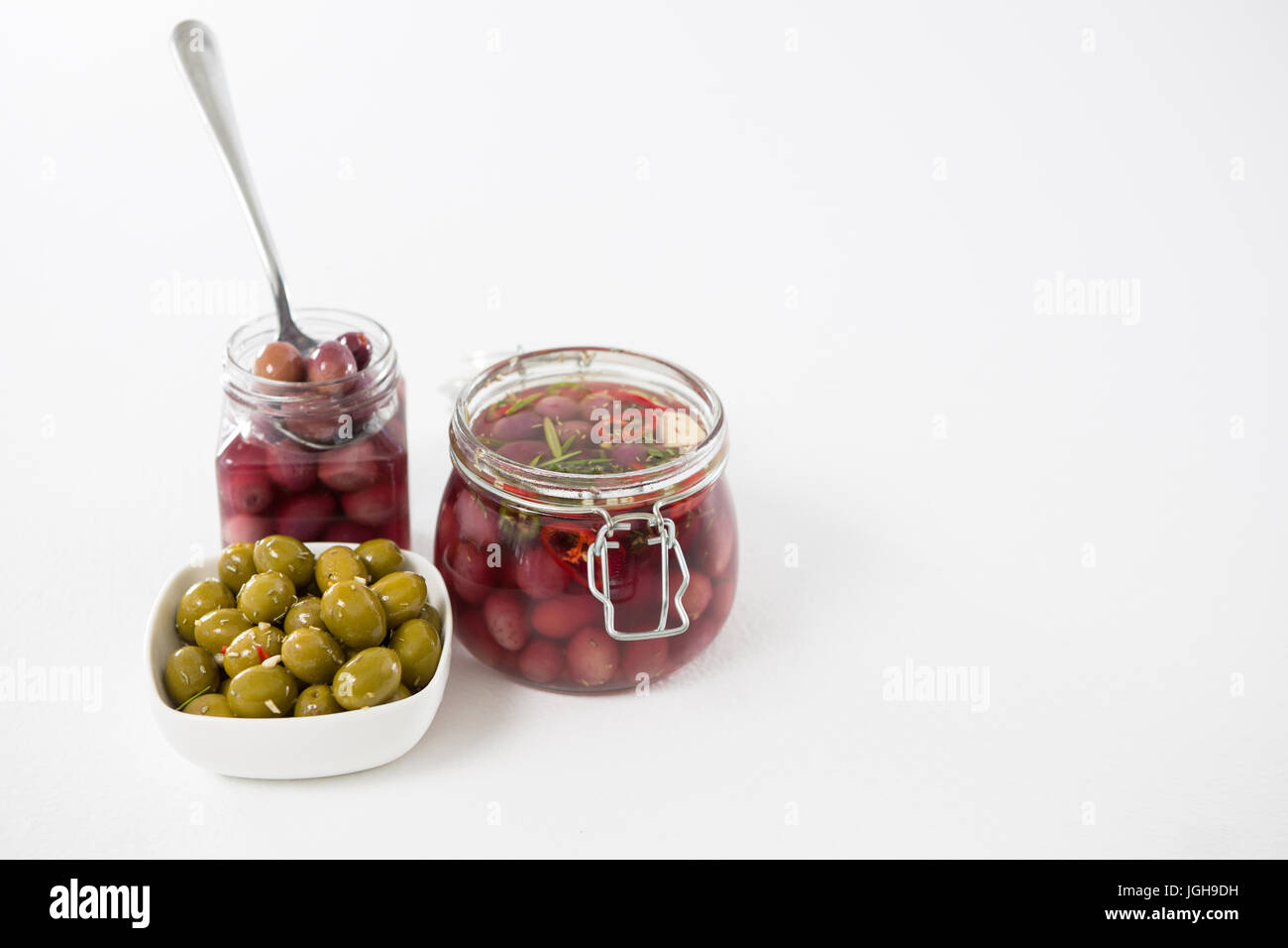 Olive in salamoia in vaso e ciotola contro uno sfondo bianco Foto Stock