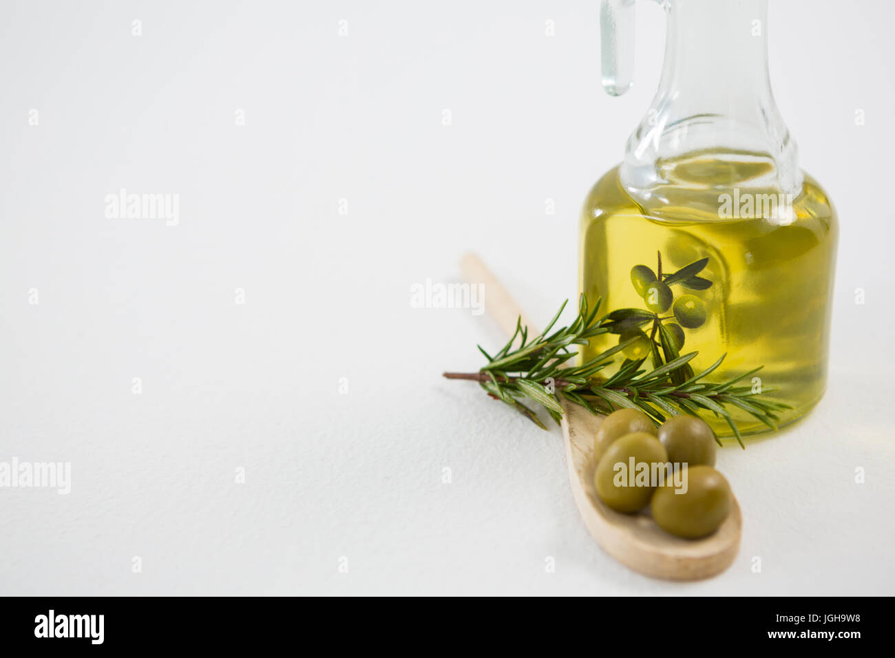 Olive marinate con bottiglia di olio e le erbe contro uno sfondo bianco Foto Stock