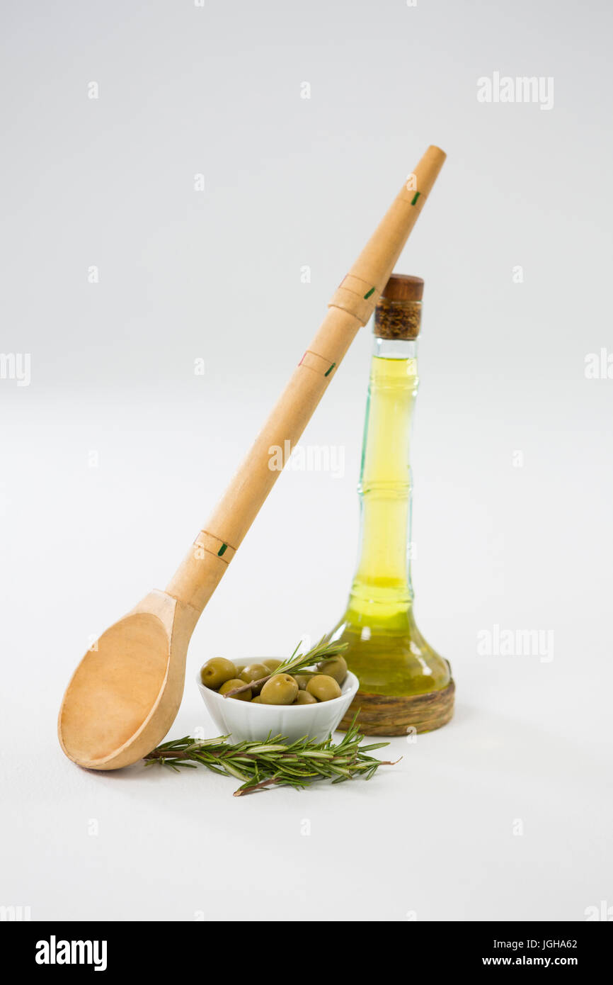 Olive marinate con bottiglia di olio e le erbe contro uno sfondo bianco Foto Stock