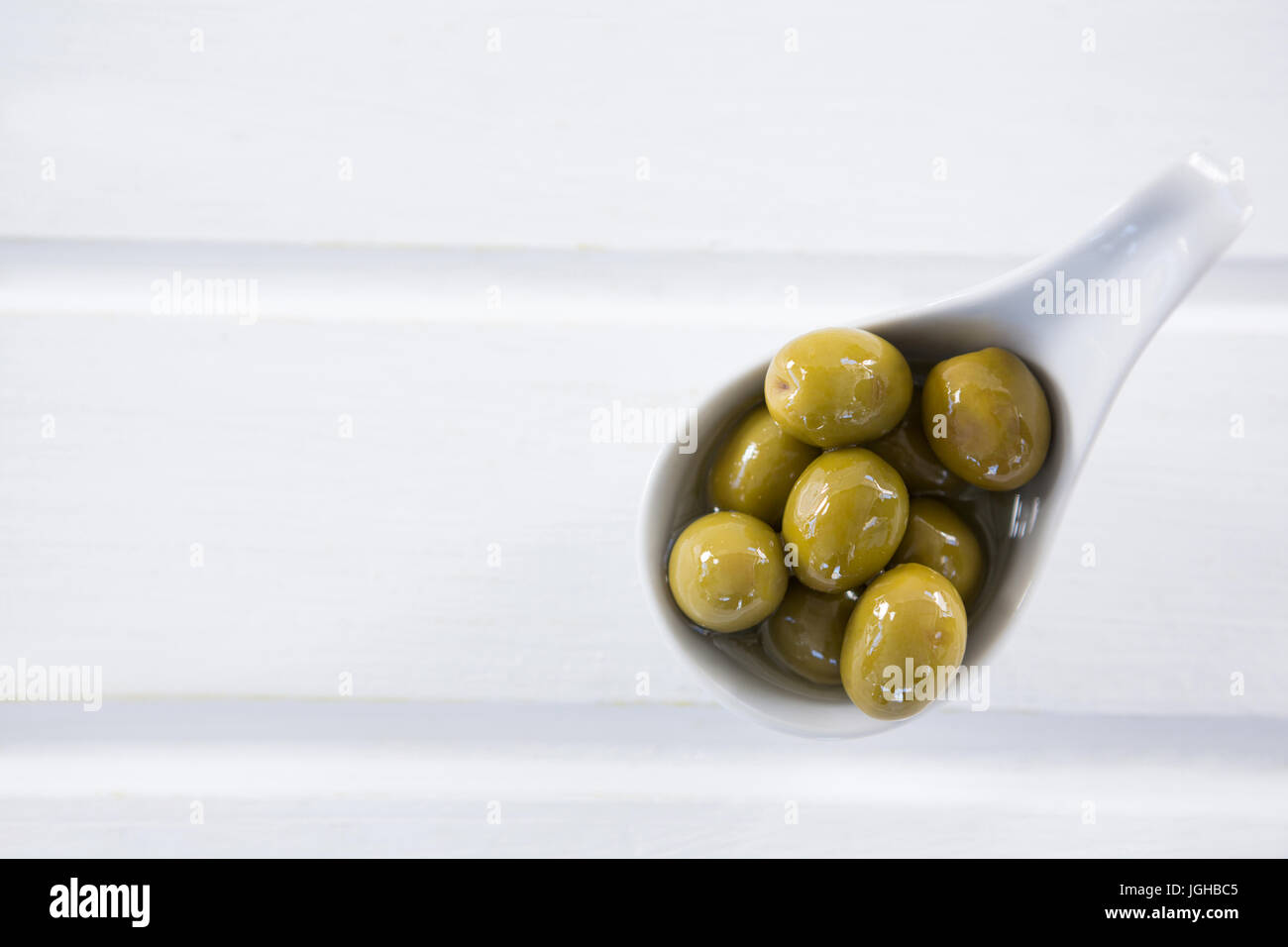 Close-up di marinata di olive verdi in un cucchiaio sul tavolo Foto Stock