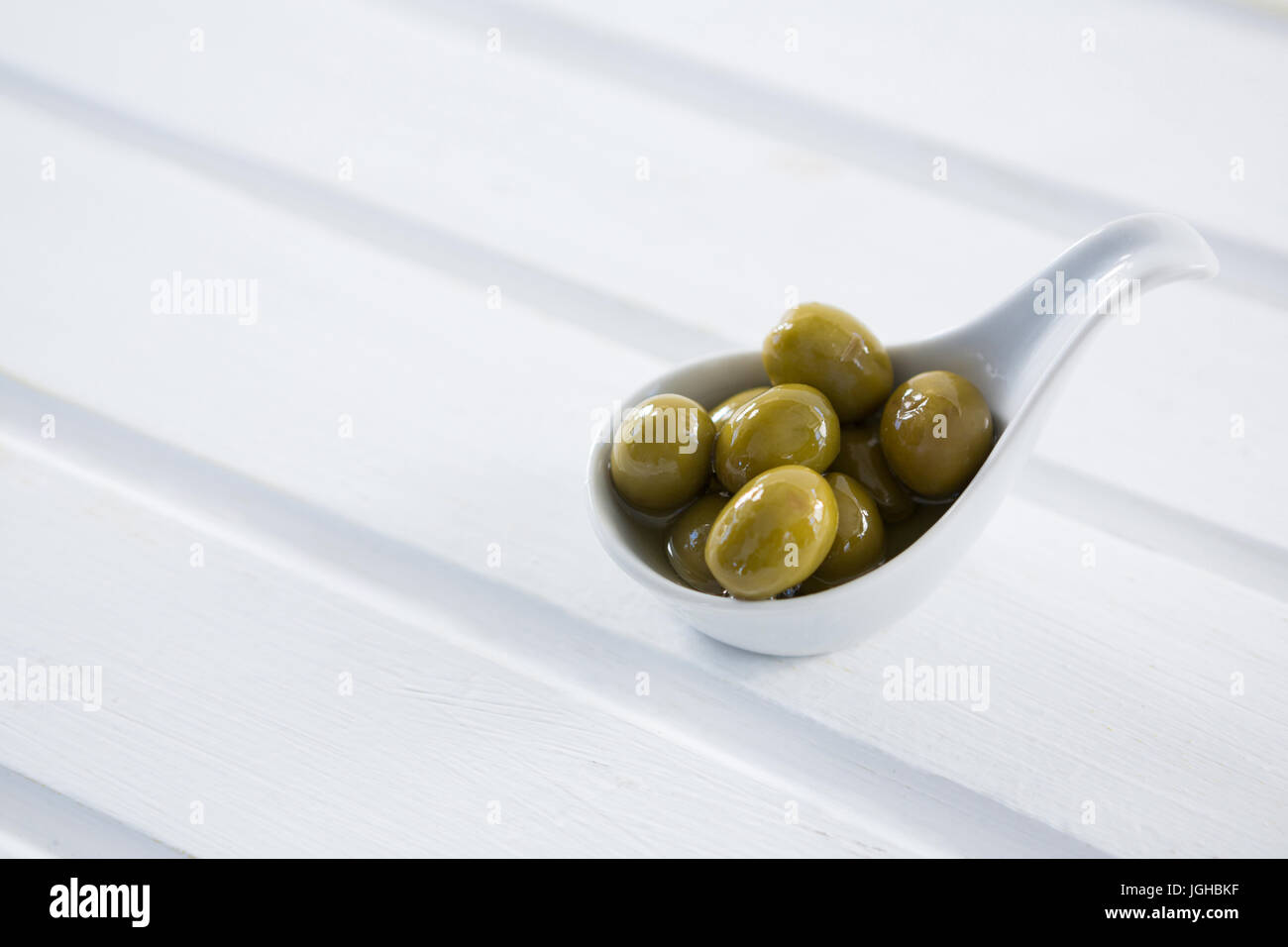 Close-up di marinata di olive verdi in un cucchiaio sul tavolo Foto Stock