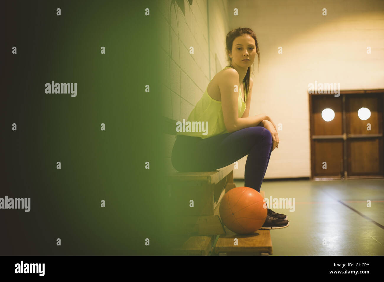 Vista laterale a piena lunghezza ritratto femminile di basket giocatore seduto sul banco di lavoro Foto Stock