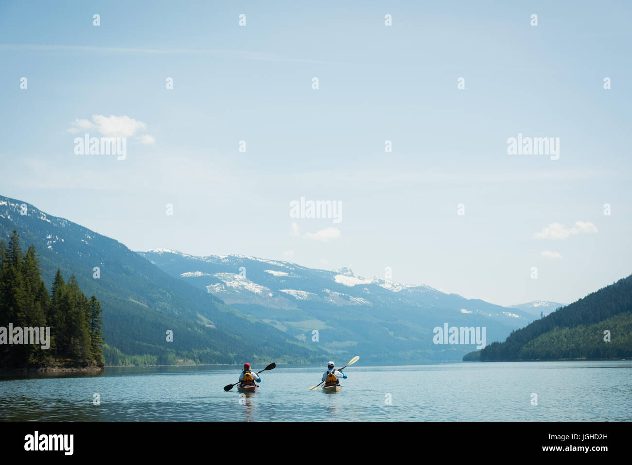 A metà distanza del giovane kayak nel lago in mezzo montagne contro il cielo Foto Stock