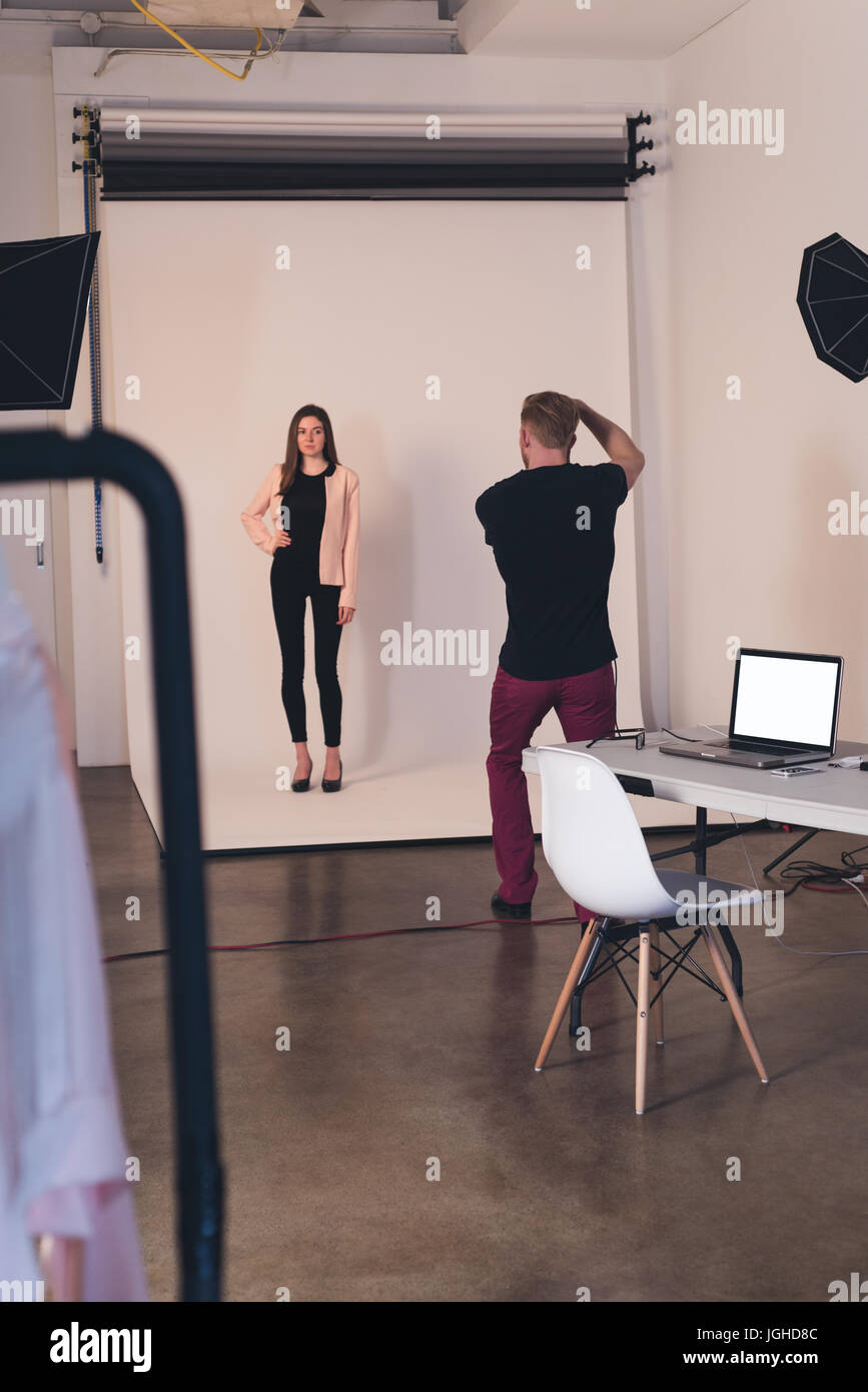 Vista posteriore del fotografo fotografare modello femminile in piedi in studio Foto Stock