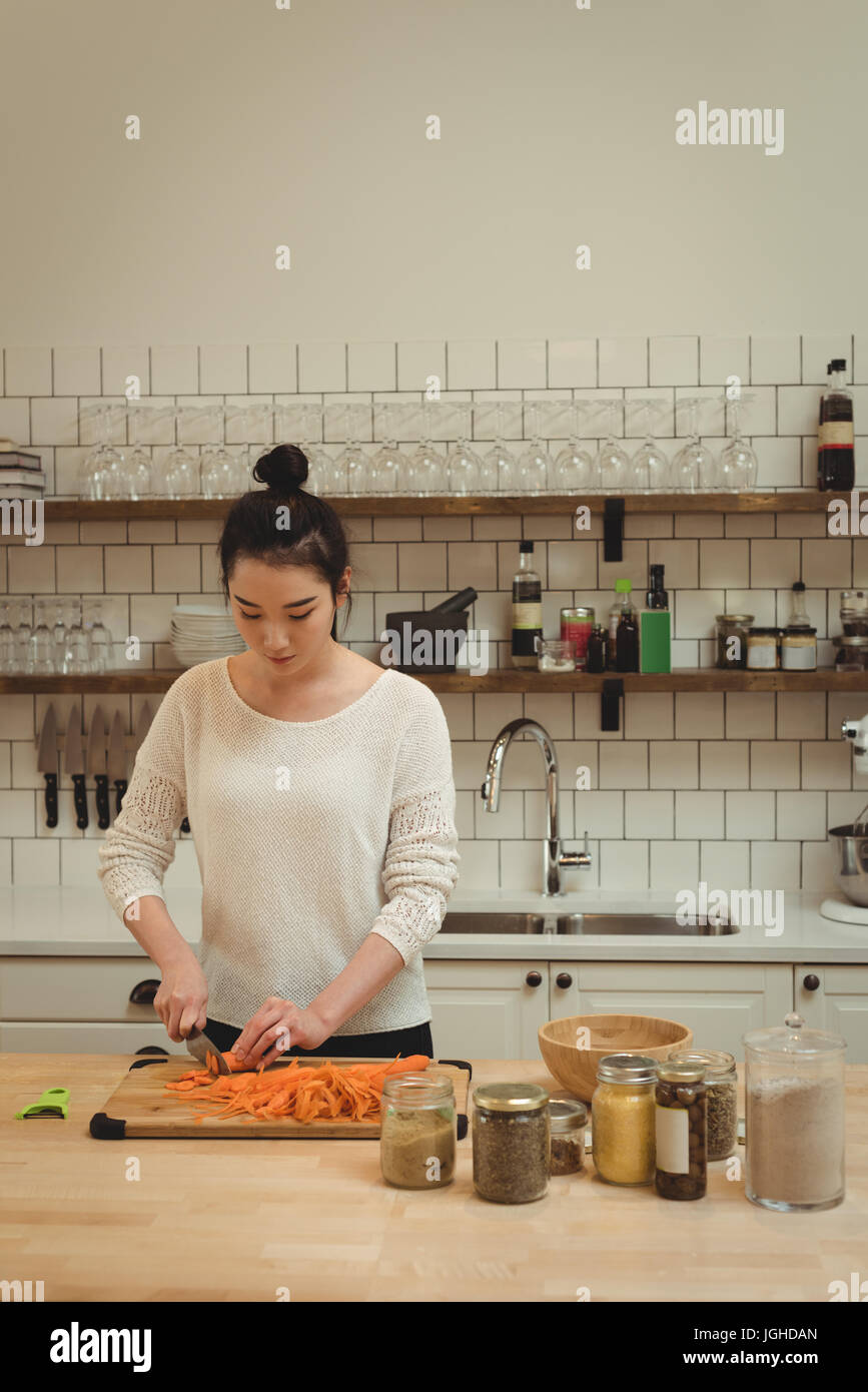 Bella donna tritare verdure in cucina a casa Foto Stock