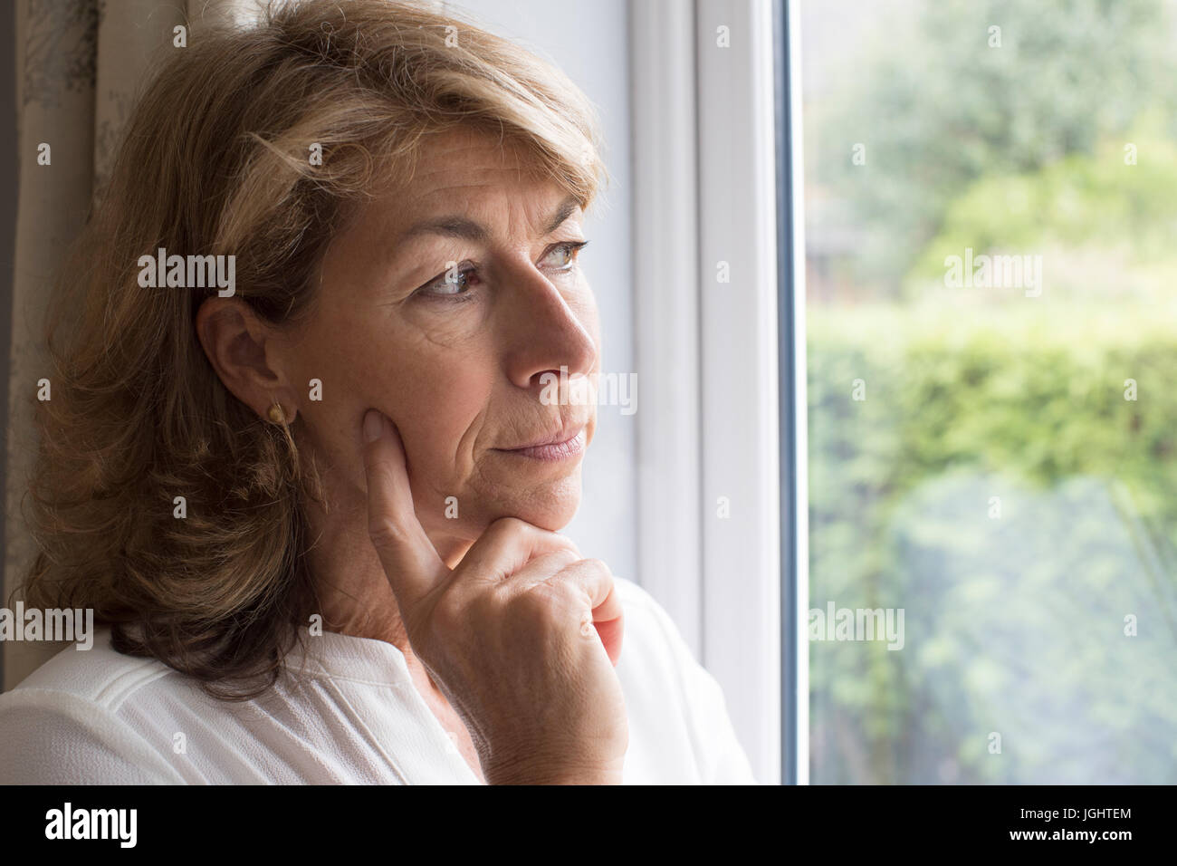 Triste la donna che soffre di agorafobia guardando fuori della finestra Foto Stock