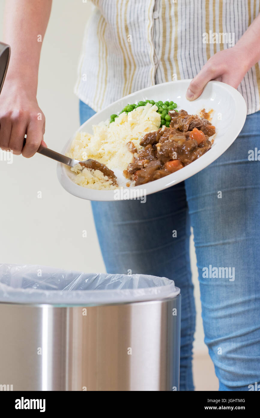 Donna di raschiatura avanzi di cibo nella spazzatura Foto Stock
