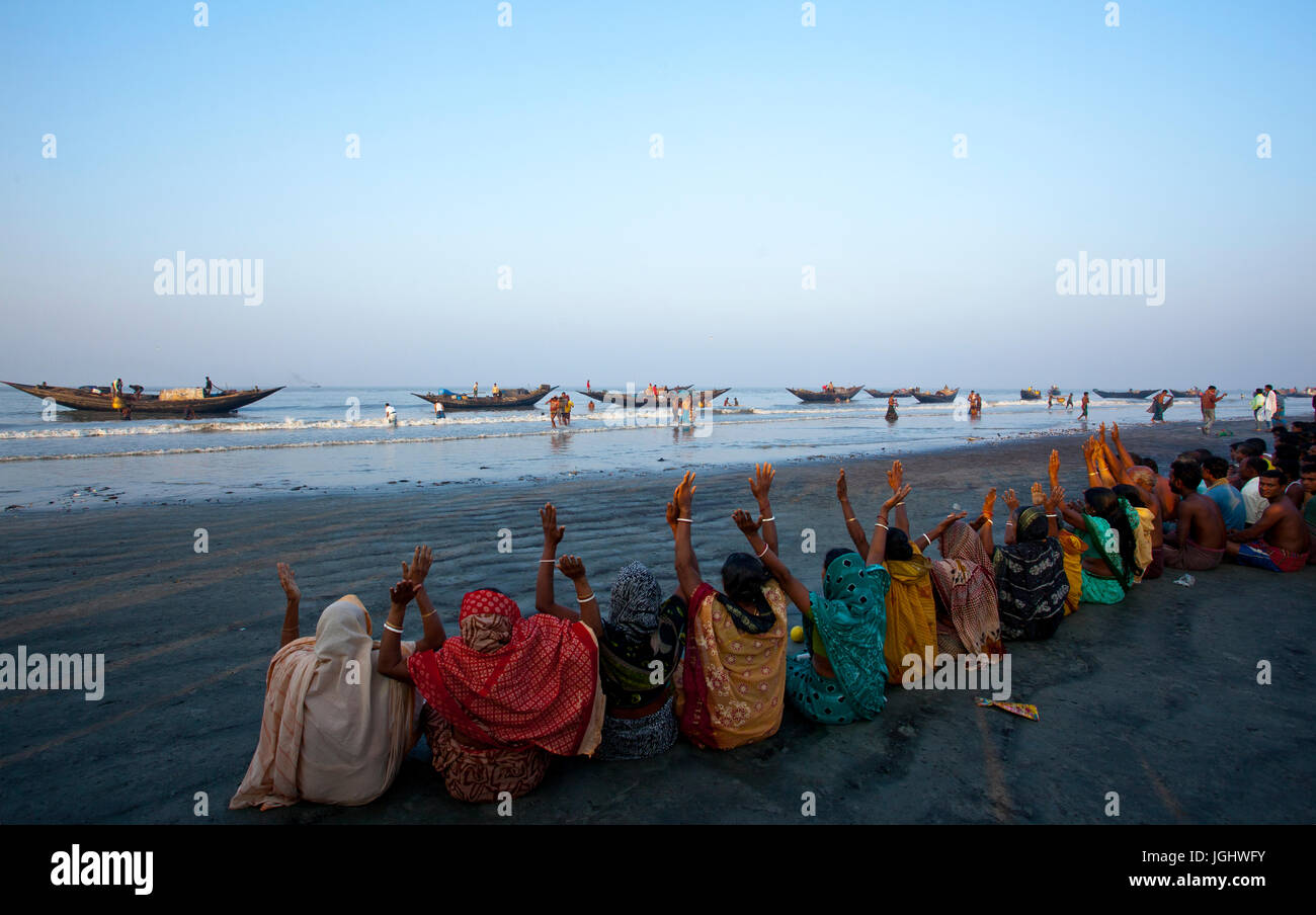 Persone provenienti da comunità indù offrono la preghiera del mattino presso la riva del Golfo del Bengala durante il rash Mela a Dublarchar in Eastern Division della S Foto Stock